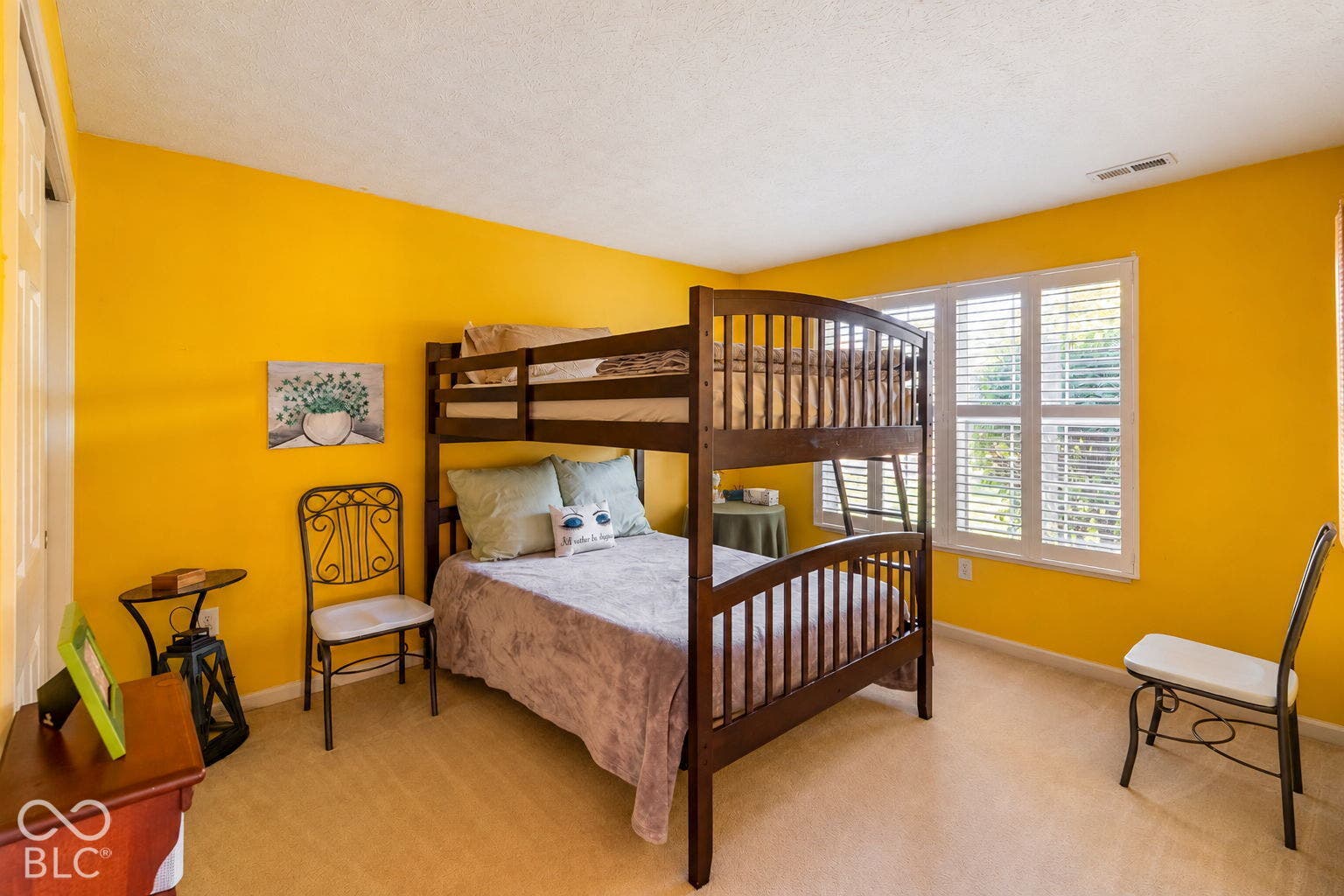 Light-colored carpeting, bright yellow walls, and a window with blinds