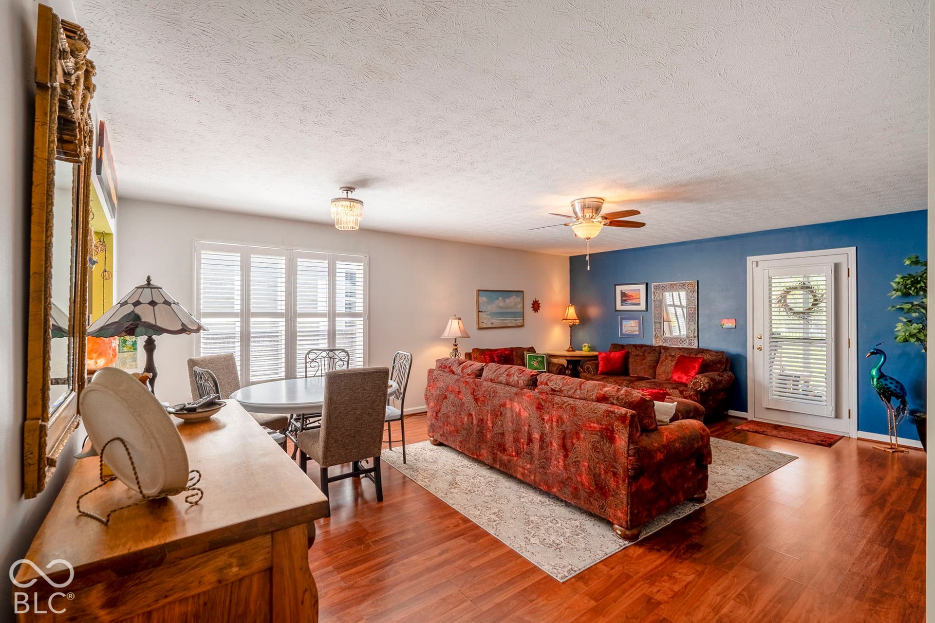 Hardwood-finish flooring, ceiling fan, white paneled door with window, and window shutters