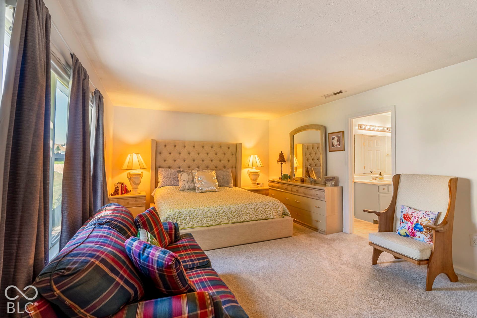 Spacious bedroom with carpeted flooring, large window, and an en-suite bathroom featuring a vanity with a single basin sink