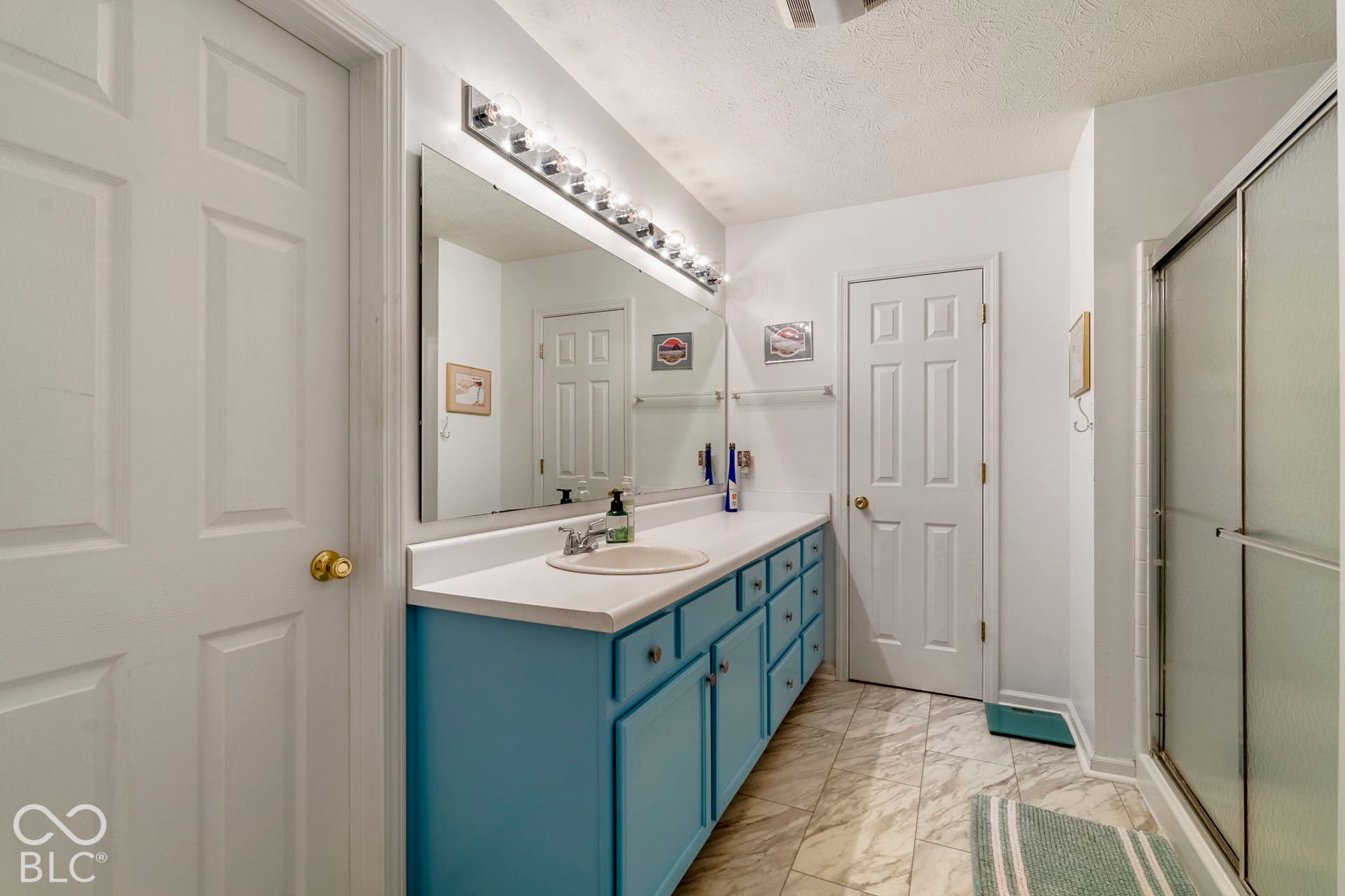 Vanity with a single basin, ample countertop space, full-width mirror, and multi-bulb vanity lighting