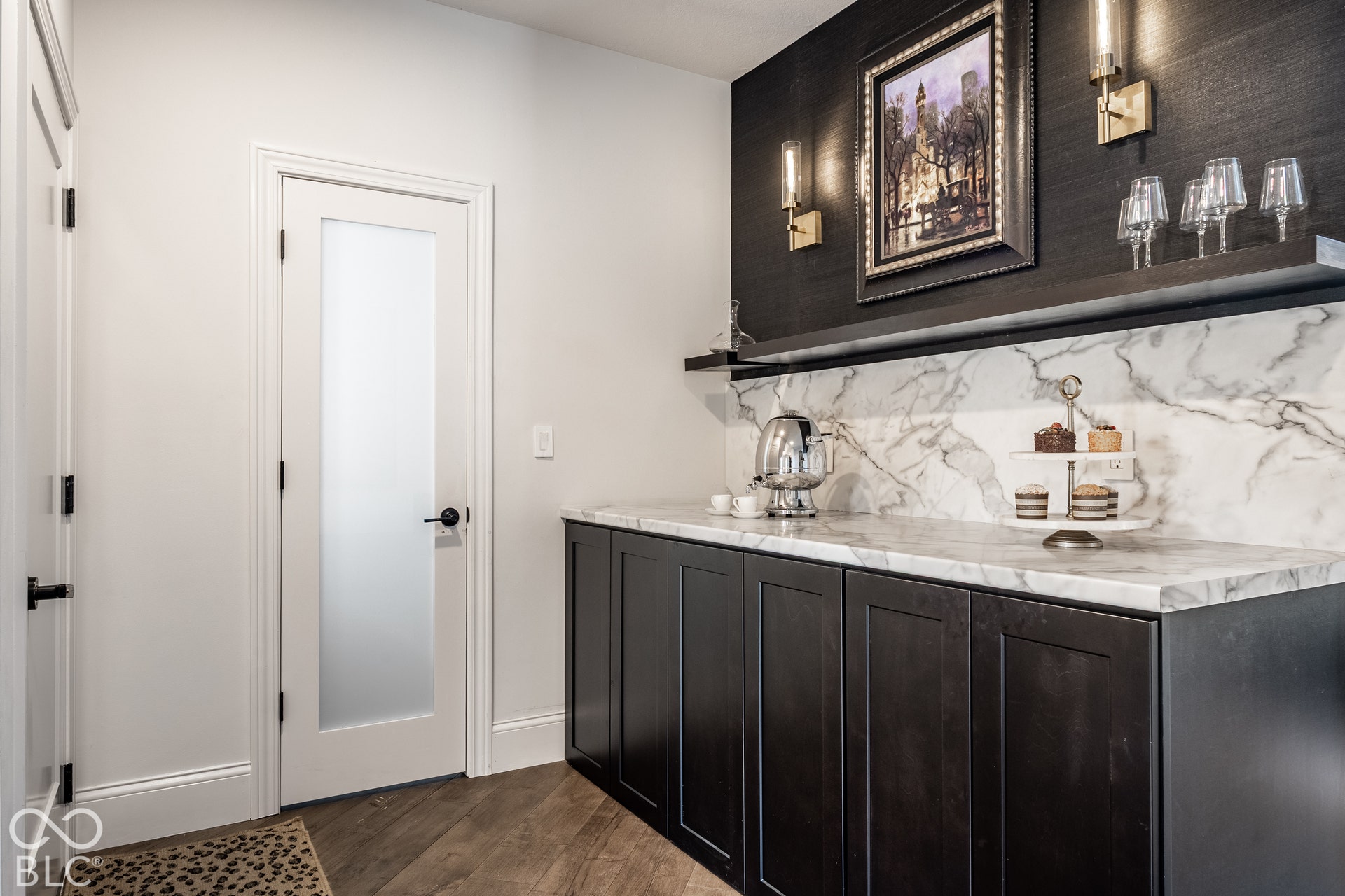 Built-in cabinetry with a stone countertop and backsplash, floating shelves, and wall sconces. Features a hidden laundry feature with soft close doors.