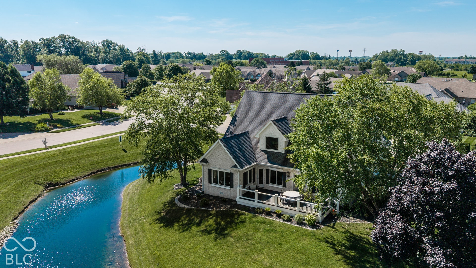 Exterior featuring a deck, surrounding landscaping, and a pond