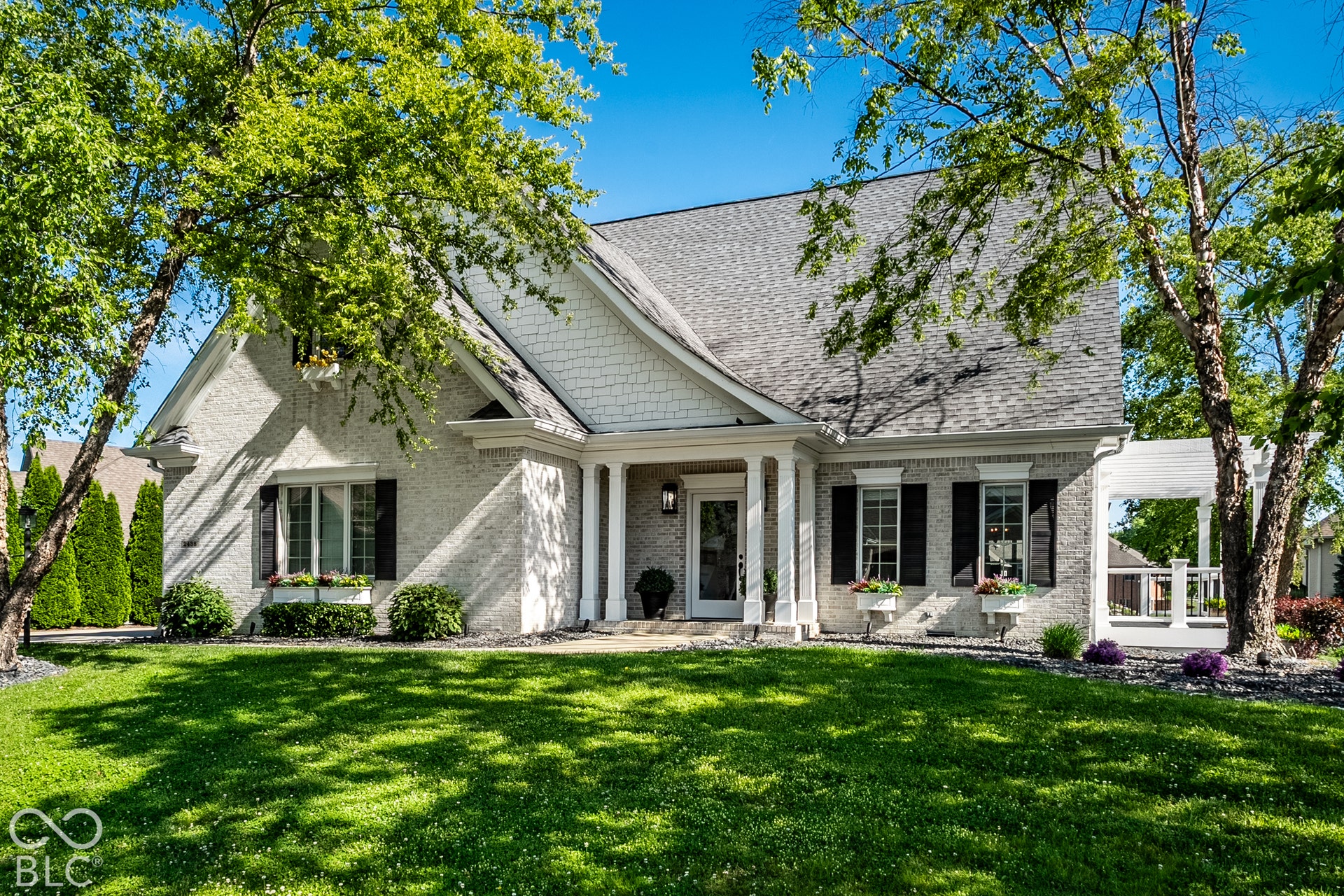 Upgraded White Brick and white motor exterior with black shutters and a covered entry features a timeless entry.