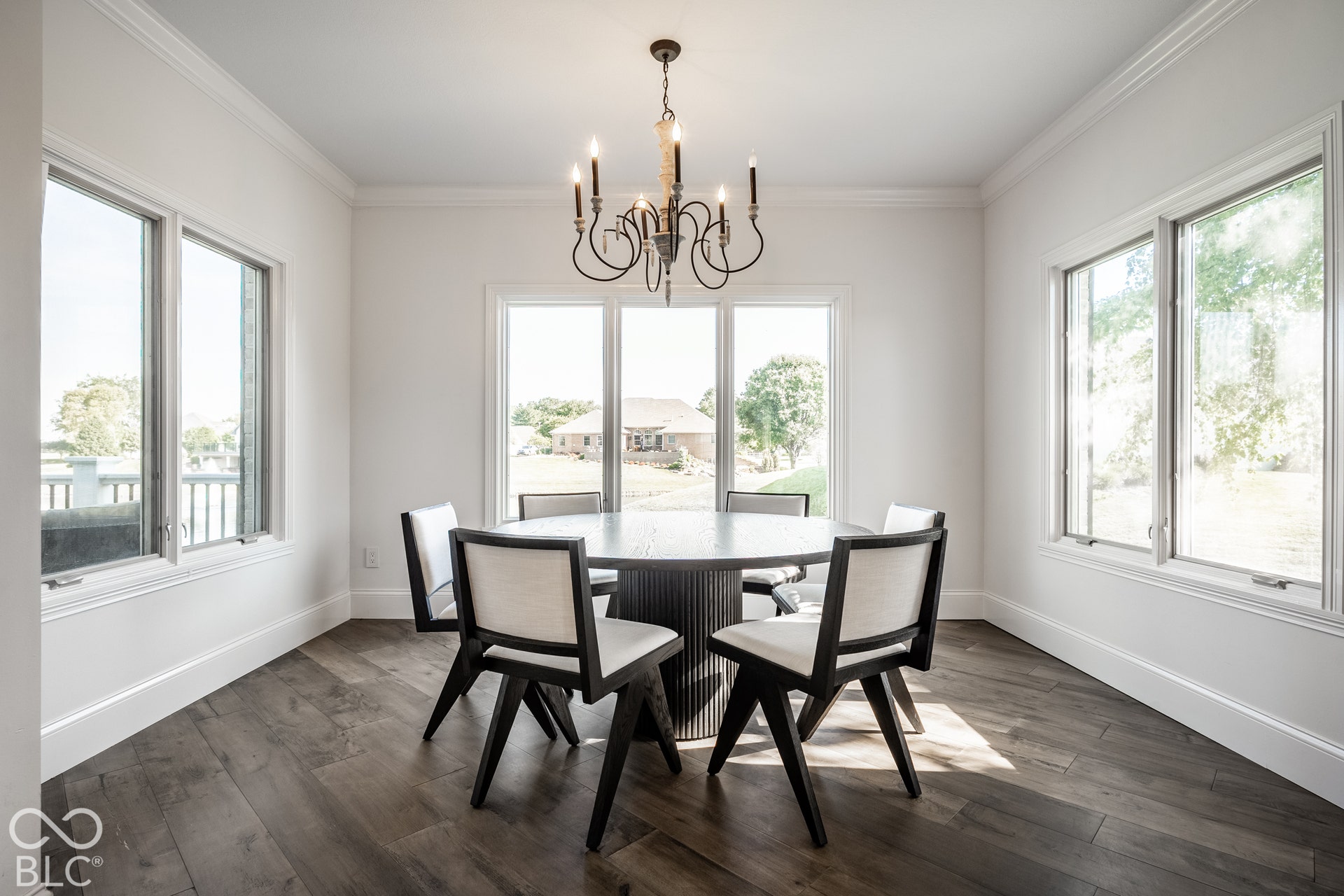 This sunroom used as a breakfast room has Wood-finish flooring with crisp white baseboards and multiple windows.