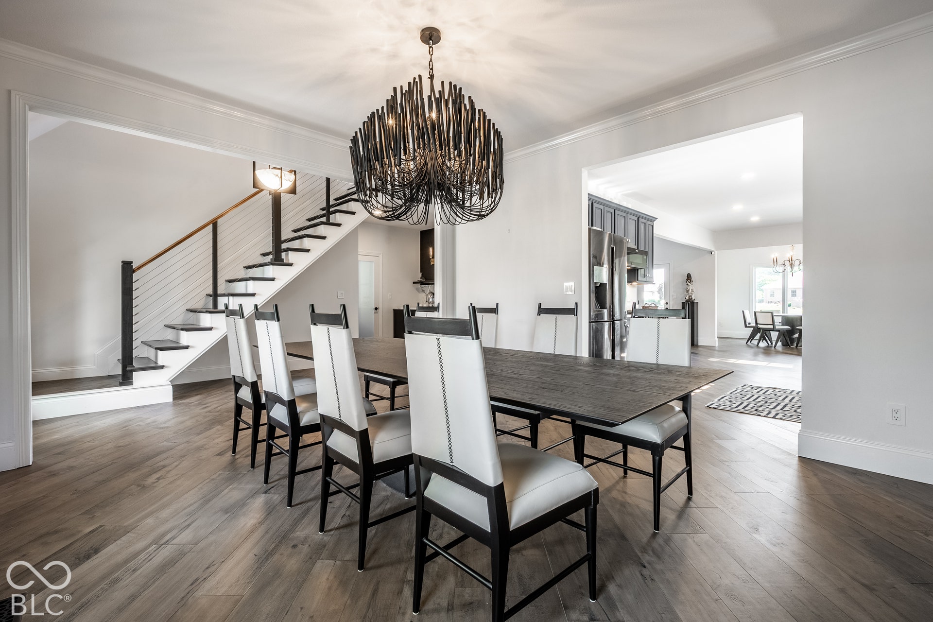 Open-concept dining area with wood-finish flooring, featuring a contemporary chandelier and crown molding