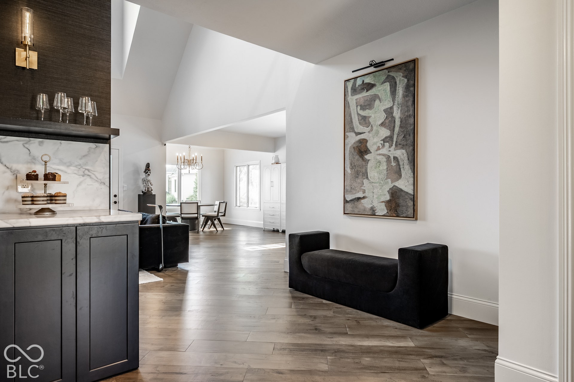 Vaulted ceilings, wood-finish flooring, dark cabinetry, and a marble-finish backsplash