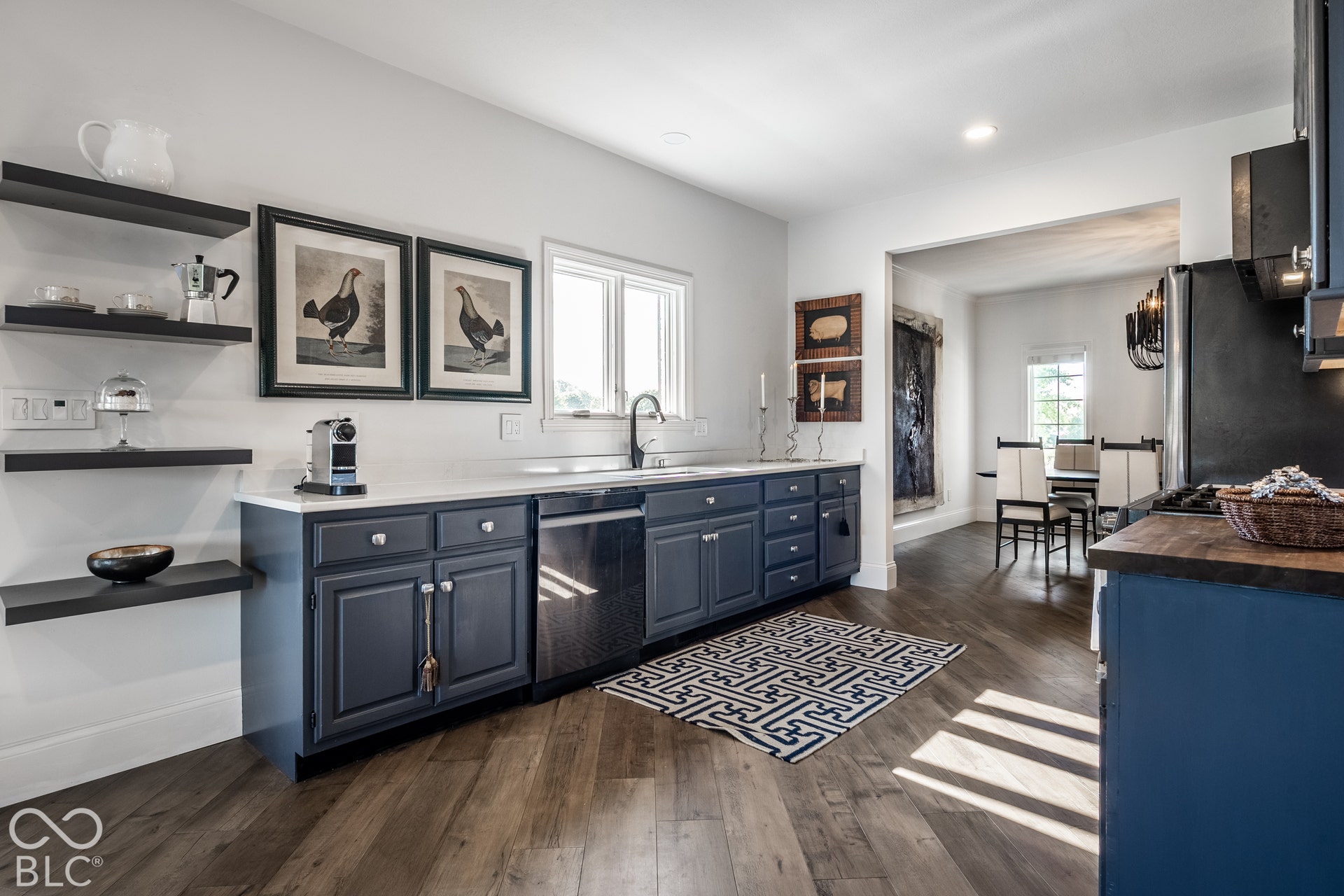 Kitchen featuring wood-finish flooring, white countertops, built-in shelving, dark blue cabinetry, and appliances.