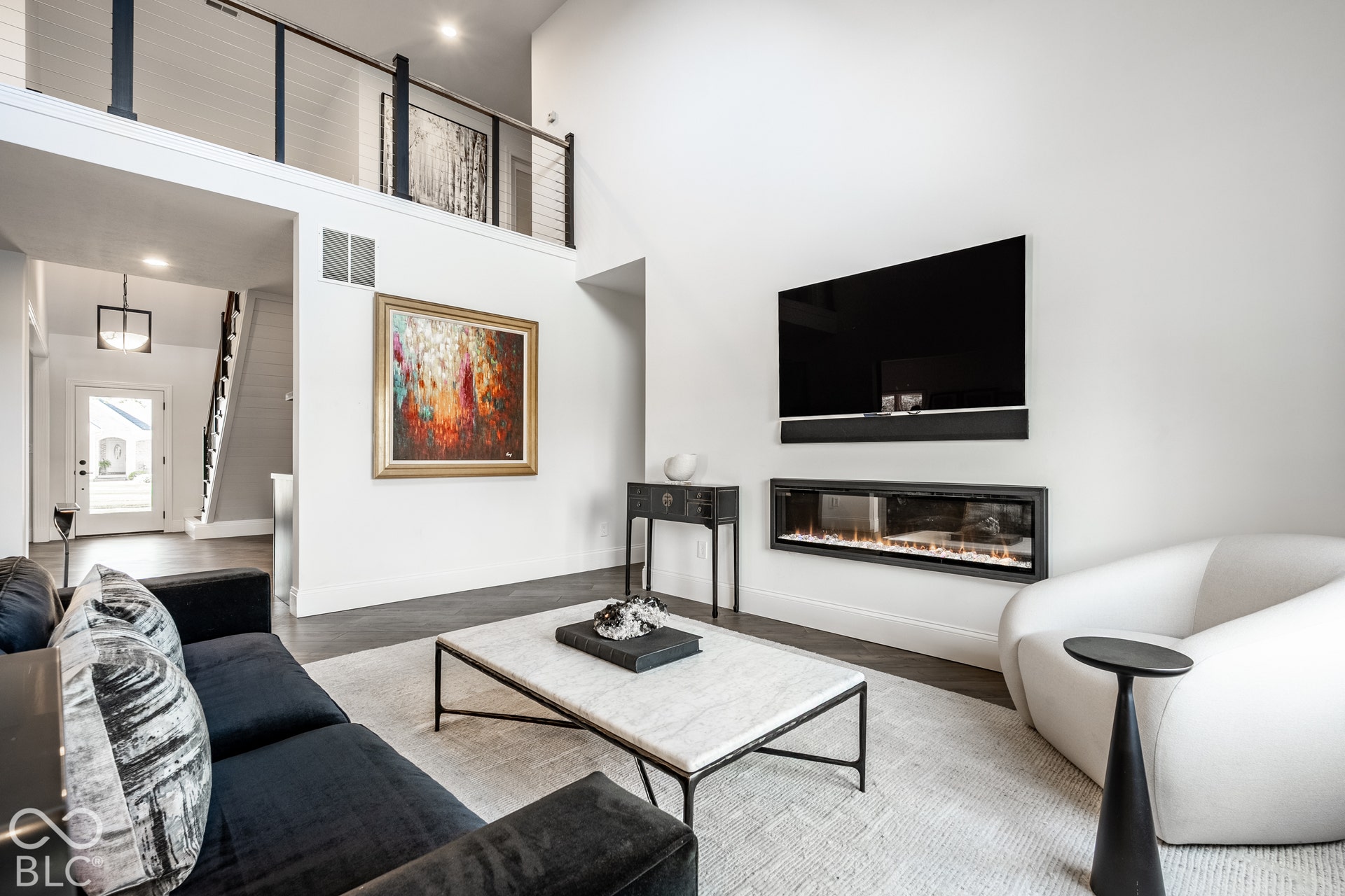Vaulted ceilings, a built-in linear fireplace, dark wood-finish flooring, and an open balcony overlooking the living area