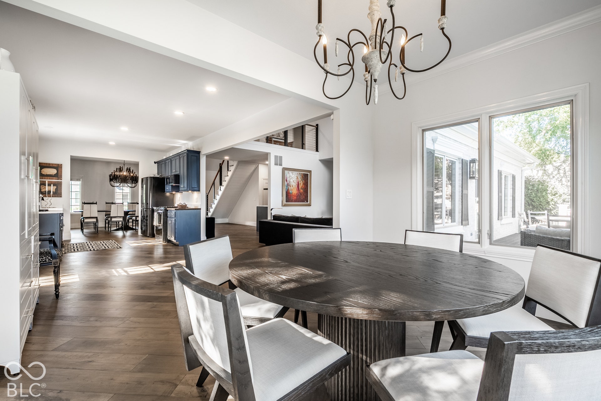 Spacious open-concept interior featuring wood-finish flooring, recessed lighting, white walls, and a prominent dining area with a modern chandelier