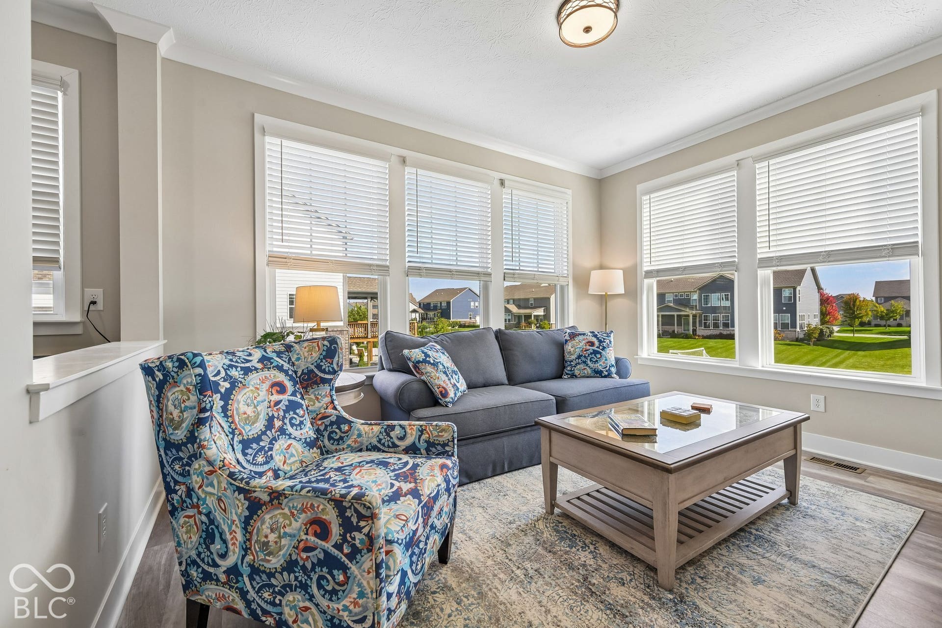 Light-filled room featuring multiple large windows, wood-finish flooring, and a semi-flush mount ceiling fixture