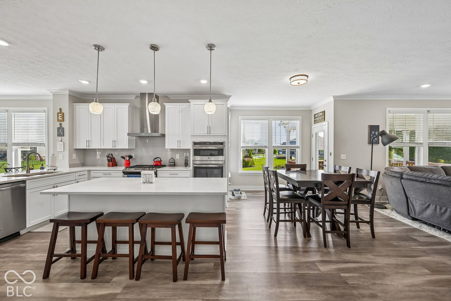 Spacious kitchen featuring white cabinetry, a large center island with seating, stainless steel appliances, and pendant lighting