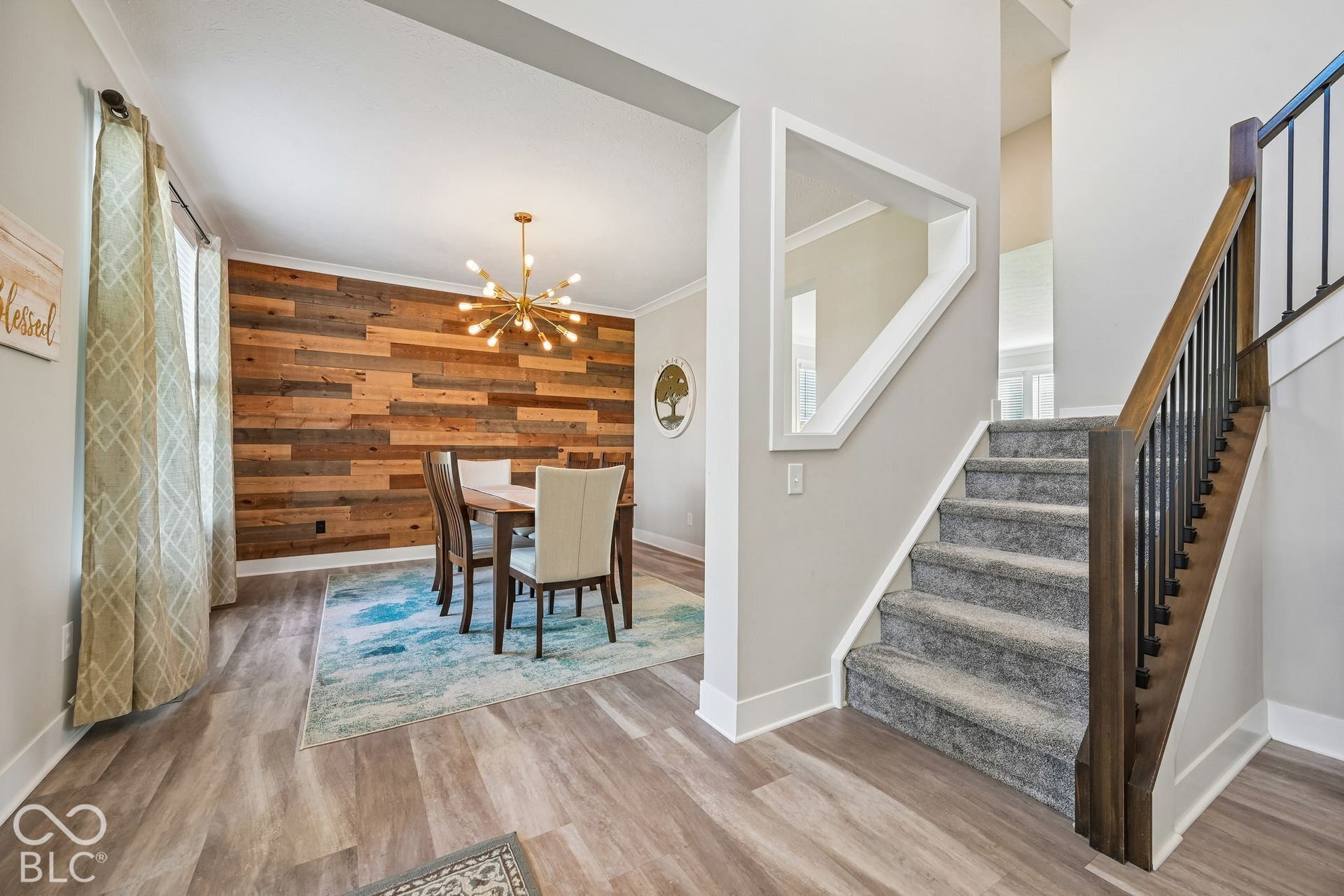 Dining area with a reclaimed wood-finish accent wall and a sputnik-style chandelier