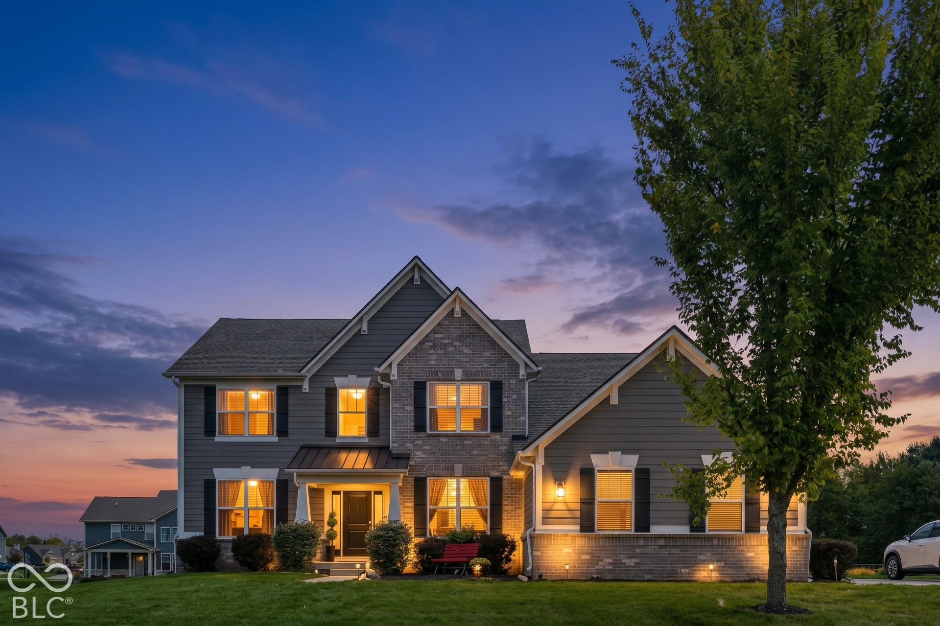 Two-story residential exterior featuring brick and siding finishes, prominent gables, and a covered front entry