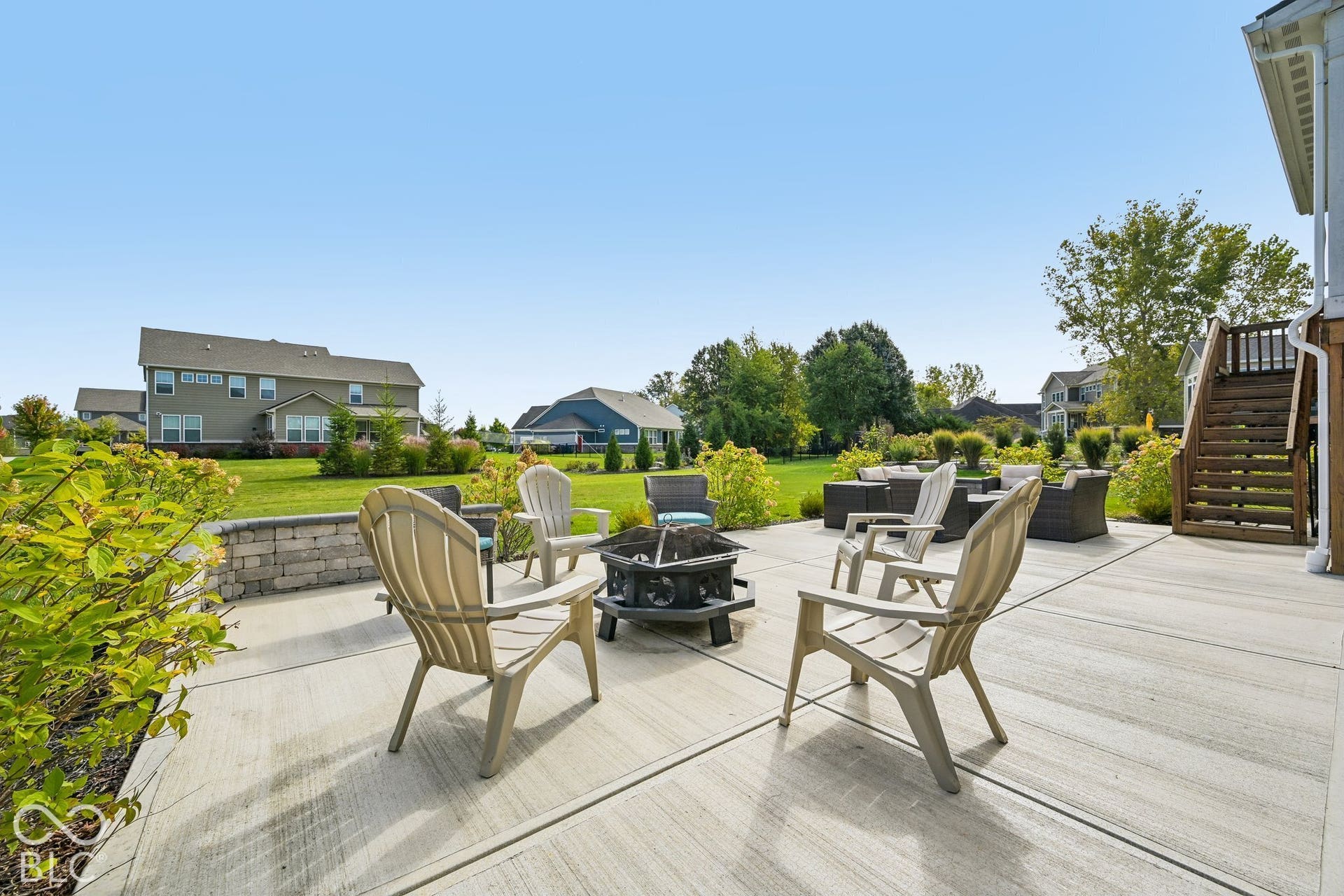 Expansive patio featuring a concrete surface, a low retaining wall, and mature landscaping
