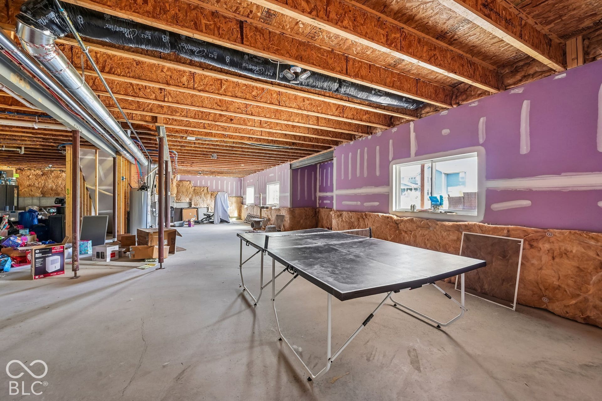 Unfinished basement with exposed ceiling joists, concrete flooring, and partial wall framing