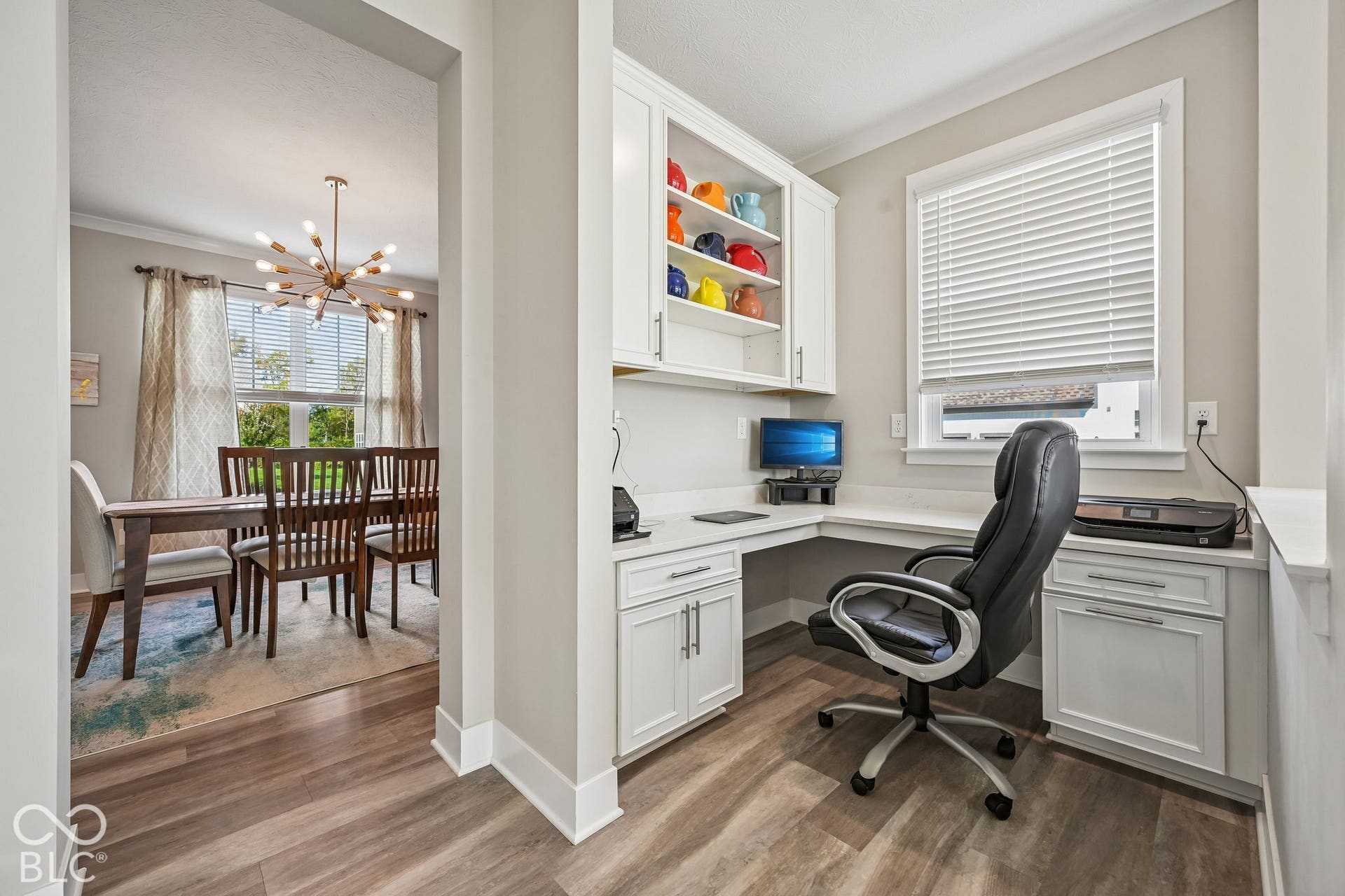 Built-in desk area featuring white cabinetry with upper shelving and wood-finish flooring