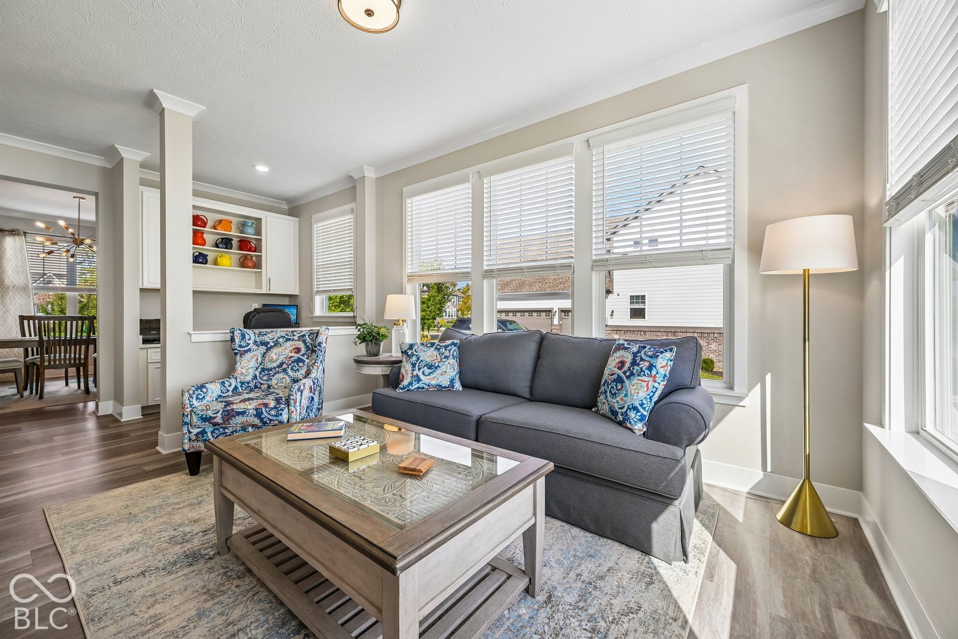 Spacious living area featuring wood-finish flooring, abundant natural light from multiple windows, crown molding, recessed lighting, and built-in cabinetry