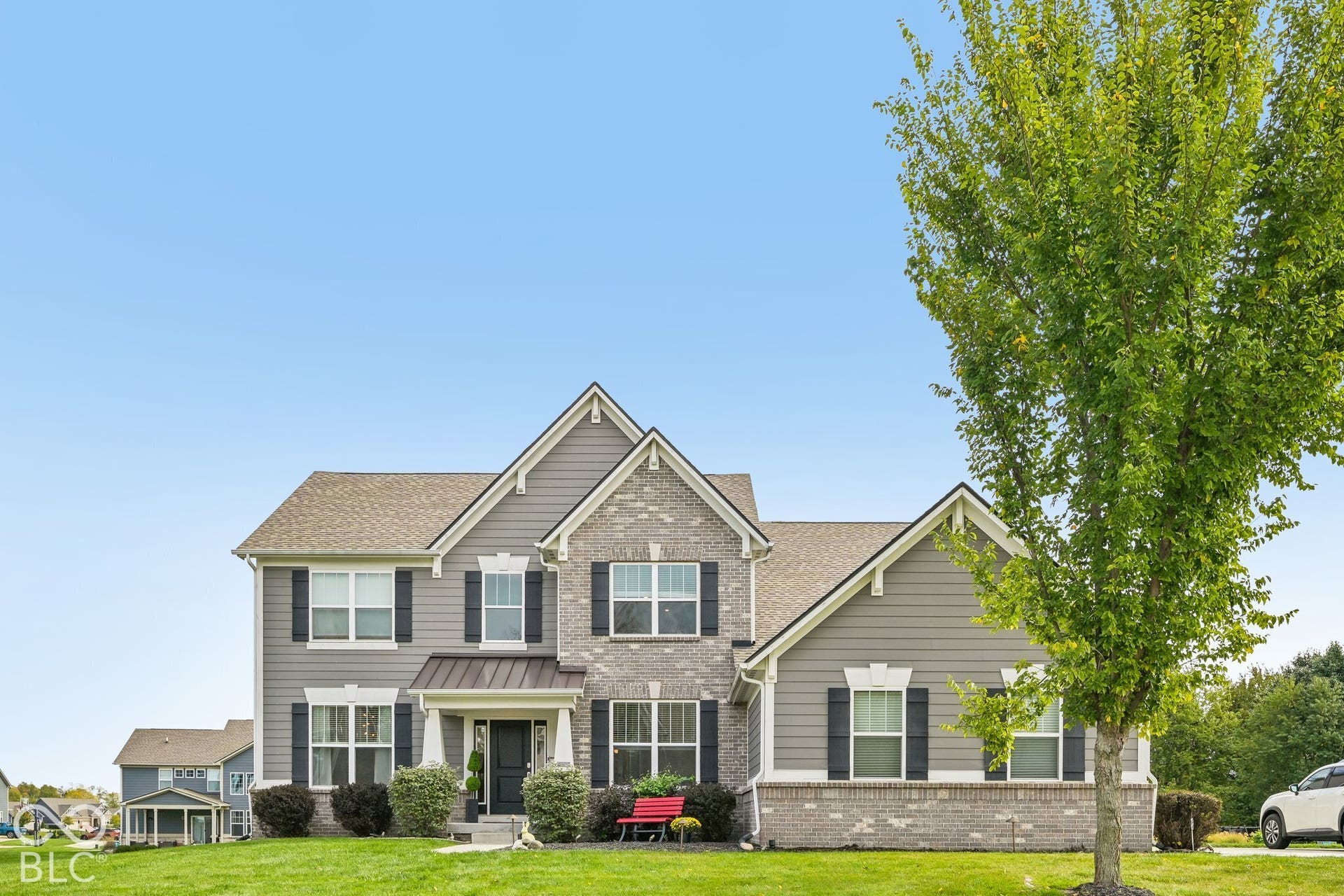 Two-story residence featuring a combination of brick and siding, a covered front entry, gabled rooflines, and dark window shutters