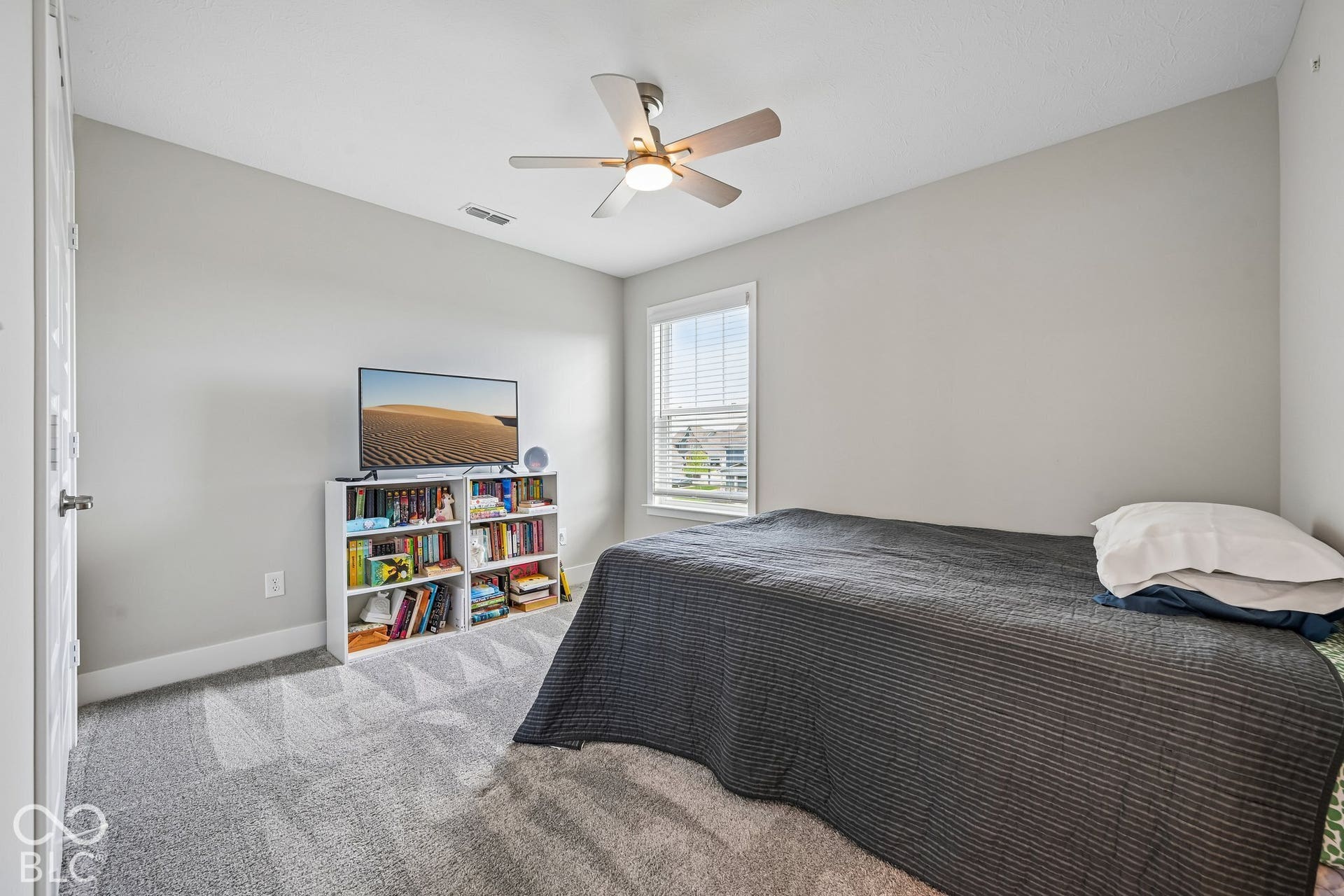 Wall-to-wall carpeted room with light gray walls, a window featuring blinds, and an overhead ceiling fan with lighting