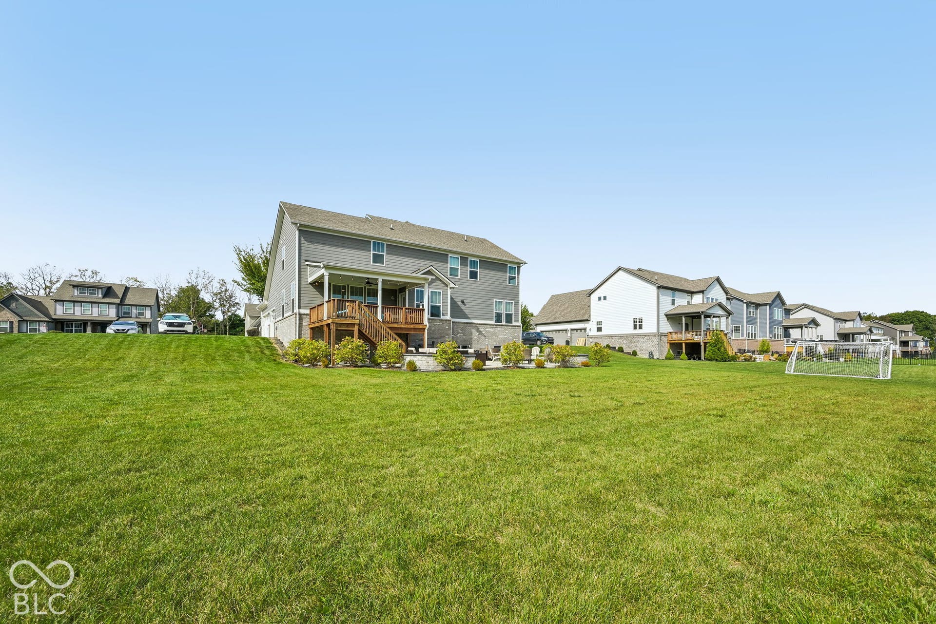 Expansive green lawn with a two-story residence featuring grey siding