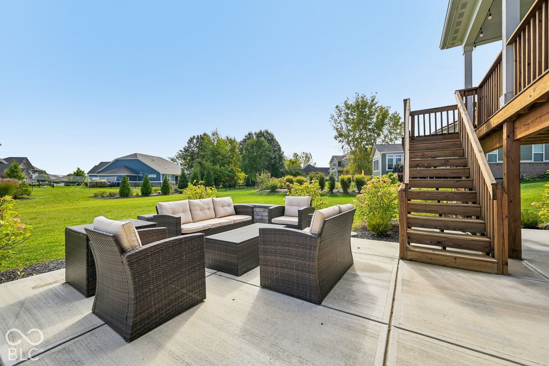 Concrete patio with a wood-finish staircase leading to an upper-level deck