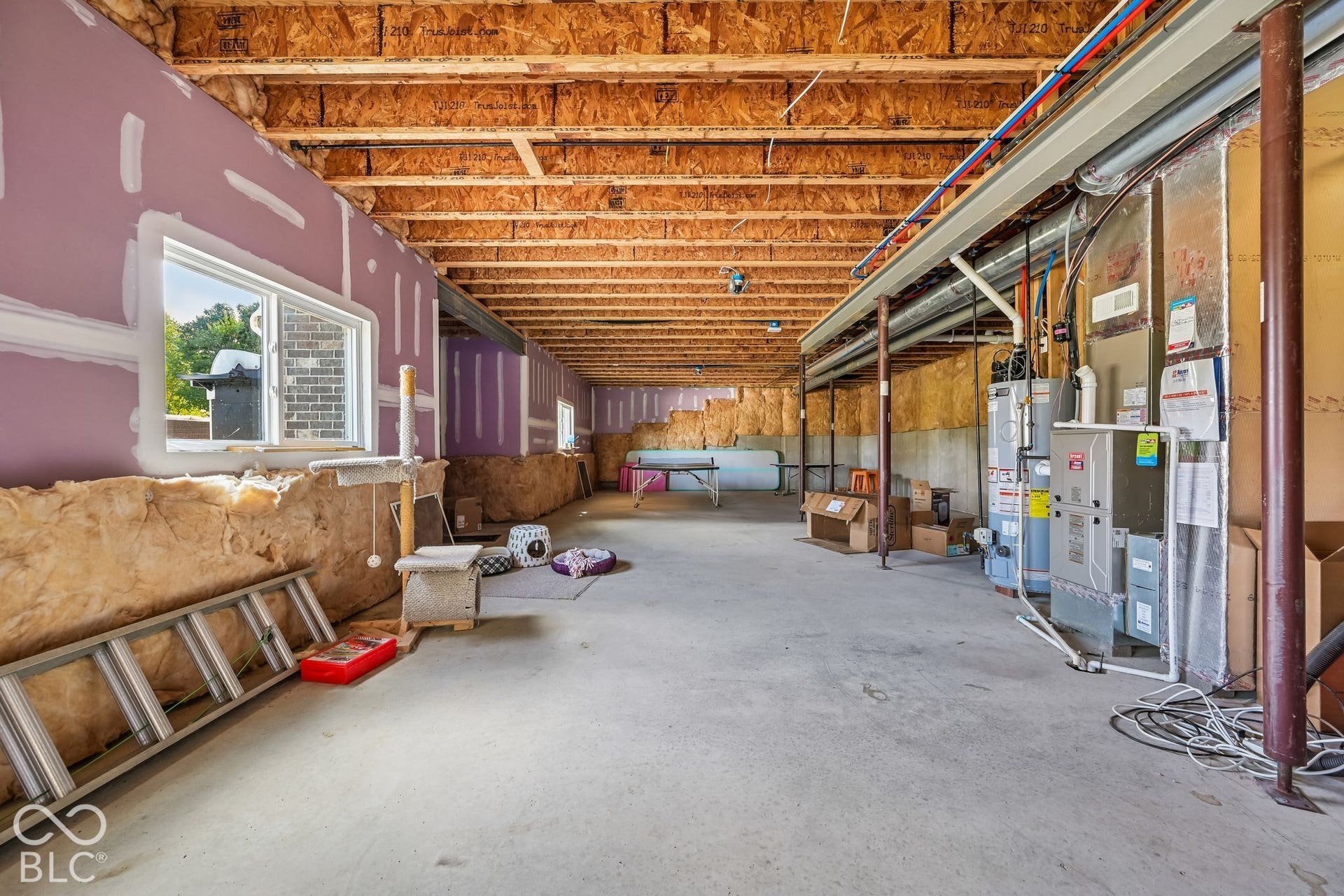 Unfinished basement with exposed ceiling joists, concrete flooring, and insulated walls