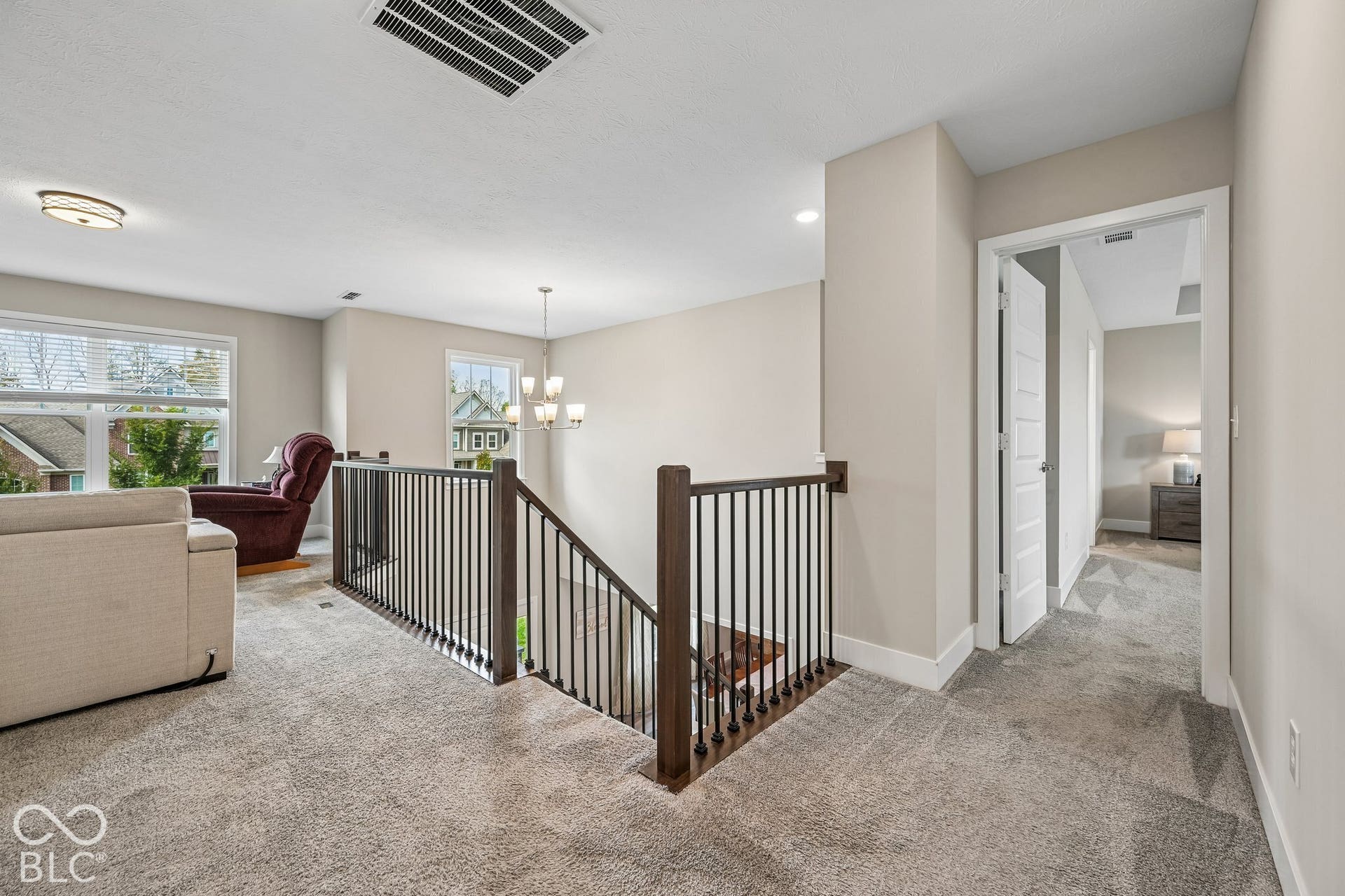 Carpeted landing featuring a wood and metal stair railing, a contemporary chandelier, recessed lighting, and white trim