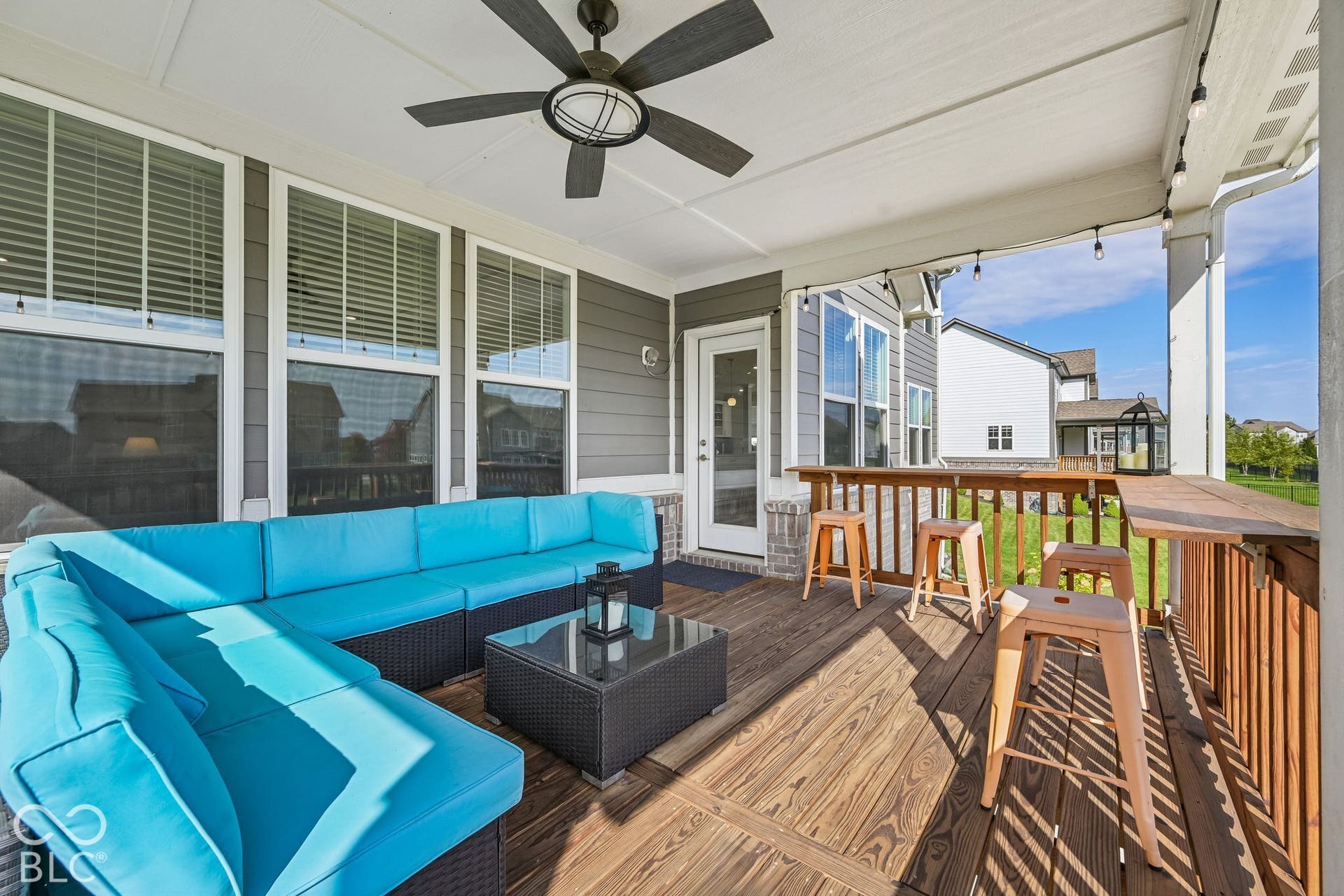 Covered outdoor deck with wood-finish flooring, ceiling fan, and built-in bar
