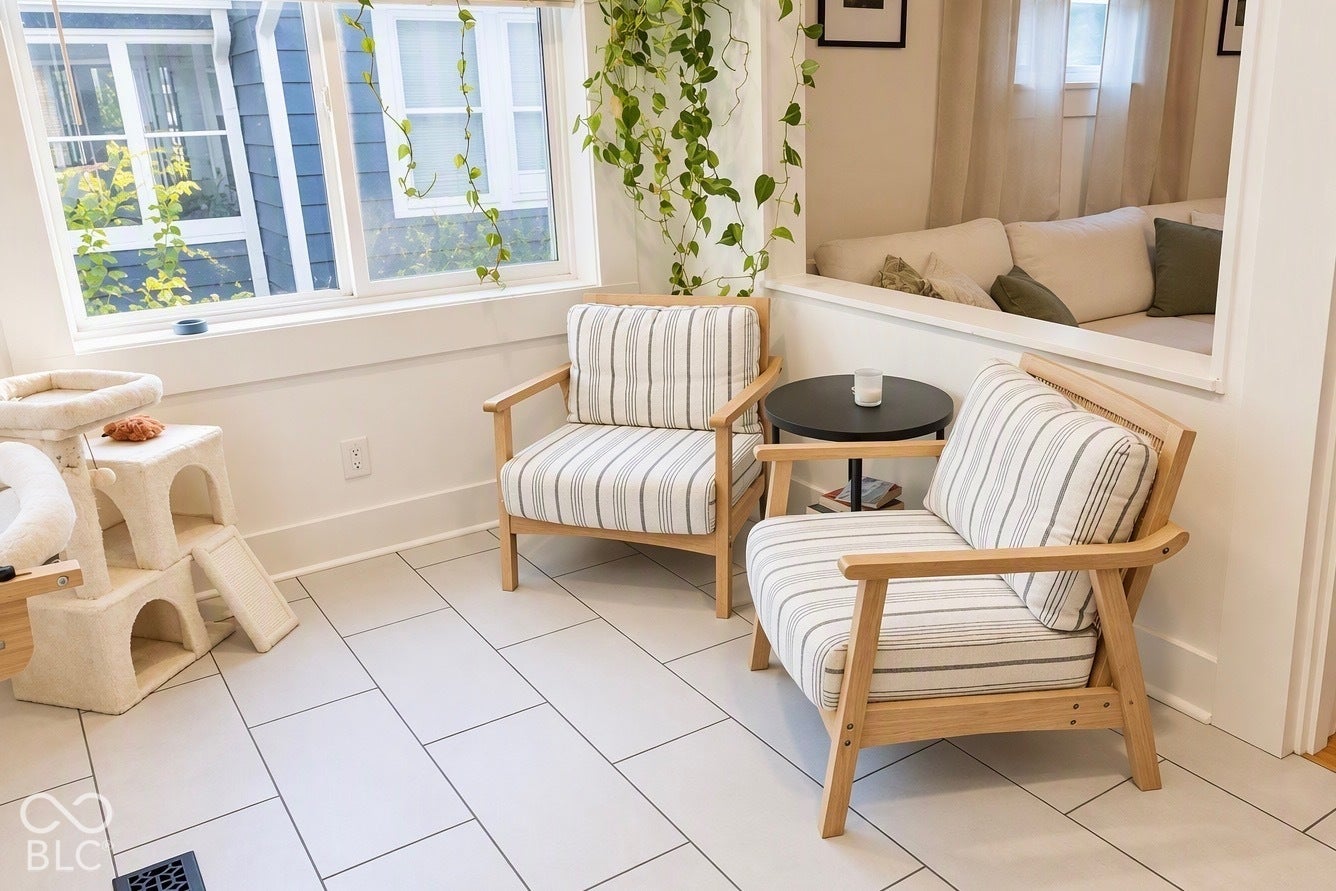 White rectangular tile flooring, large windows with white trim, built-in half-wall partition, and white wall finishes