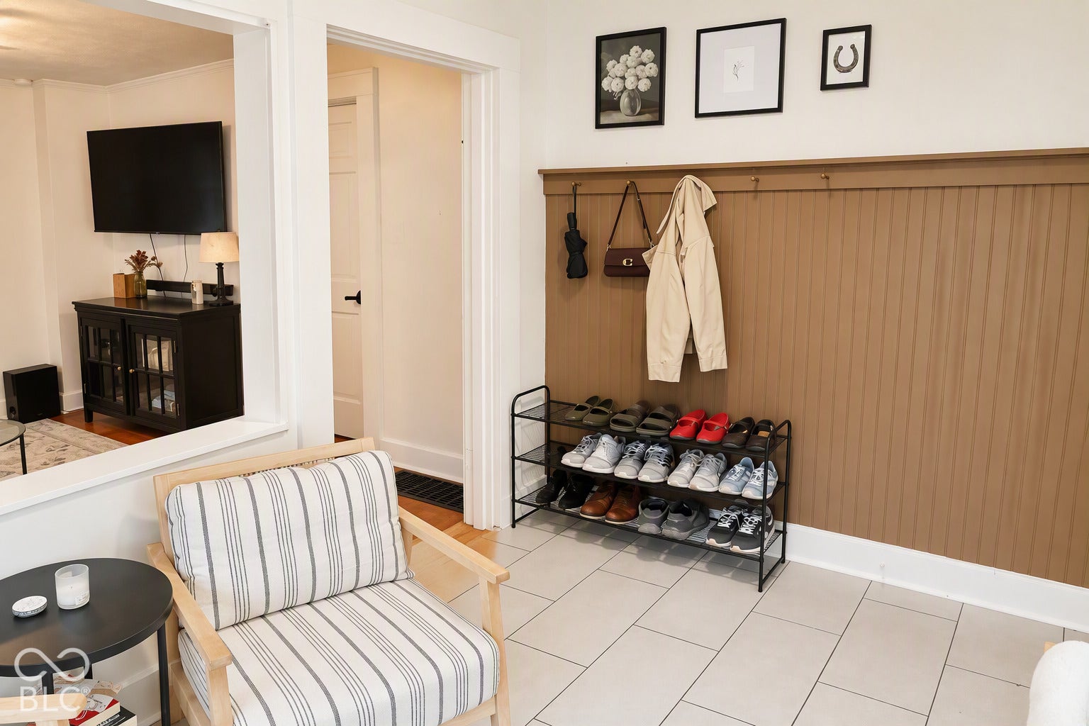 Built-in beadboard paneling with coat hooks, light-colored tile flooring, and views indoor and outdoor