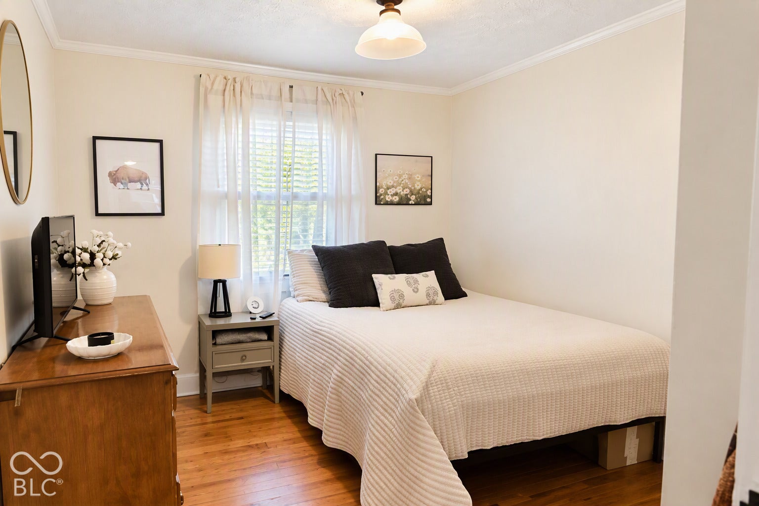 Hardwood flooring, crown molding, and a window with blinds and sheer curtains