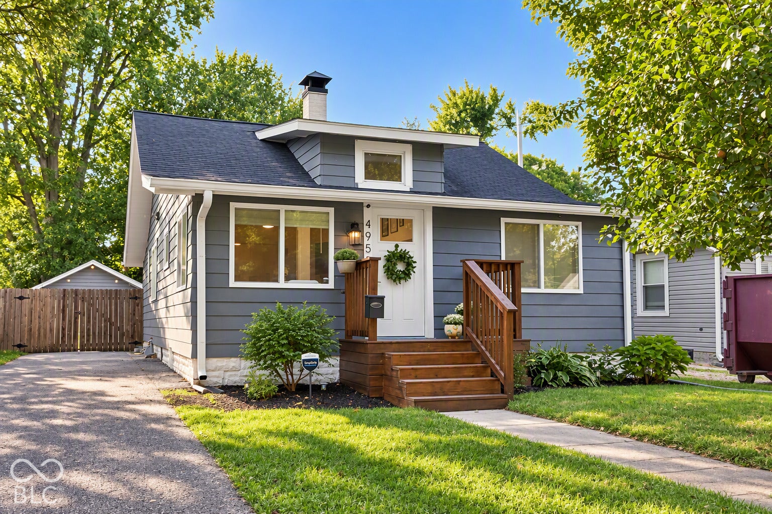 Gray siding exterior with white trim, dark asphalt shingle roof, wood steps, and a concrete pathway