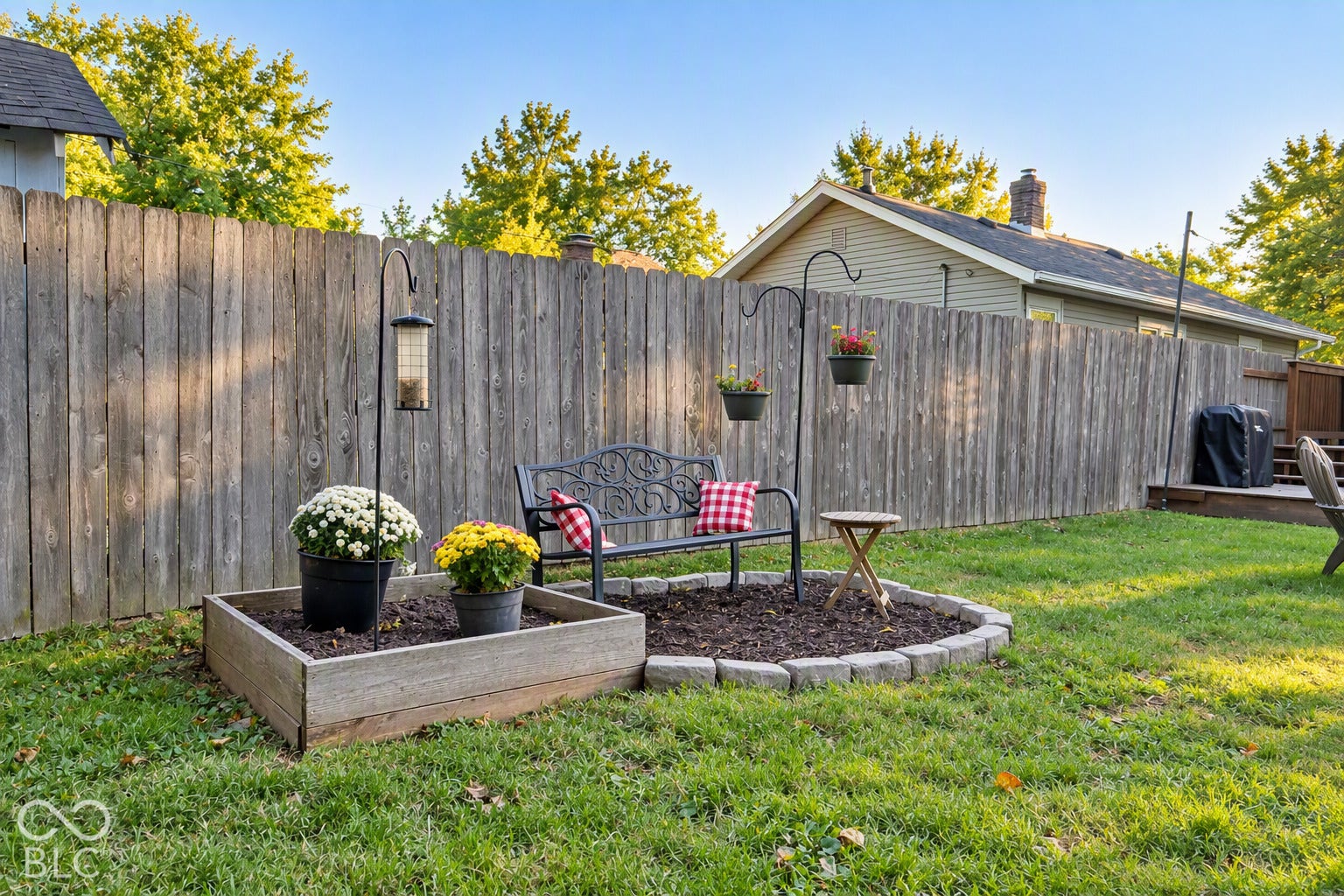 Expansive backyard featuring a wood fence, a raised garden bed, and a stone-edged planting area