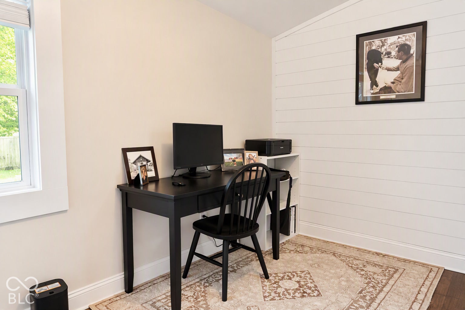 Window with white trim, light-colored walls, white shiplap accent wall, and wood-finish flooring