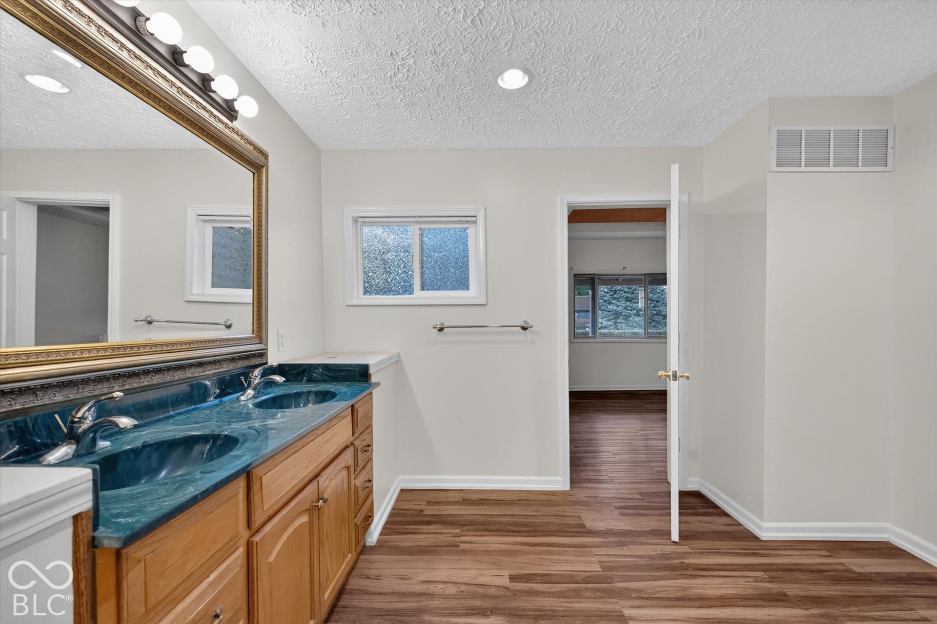 8404 Union Chapel Road, Indianapolis, IN 46240 Dual vanity with integrated sinks, wood-finish cabinetry, a large framed mirror, and LVP