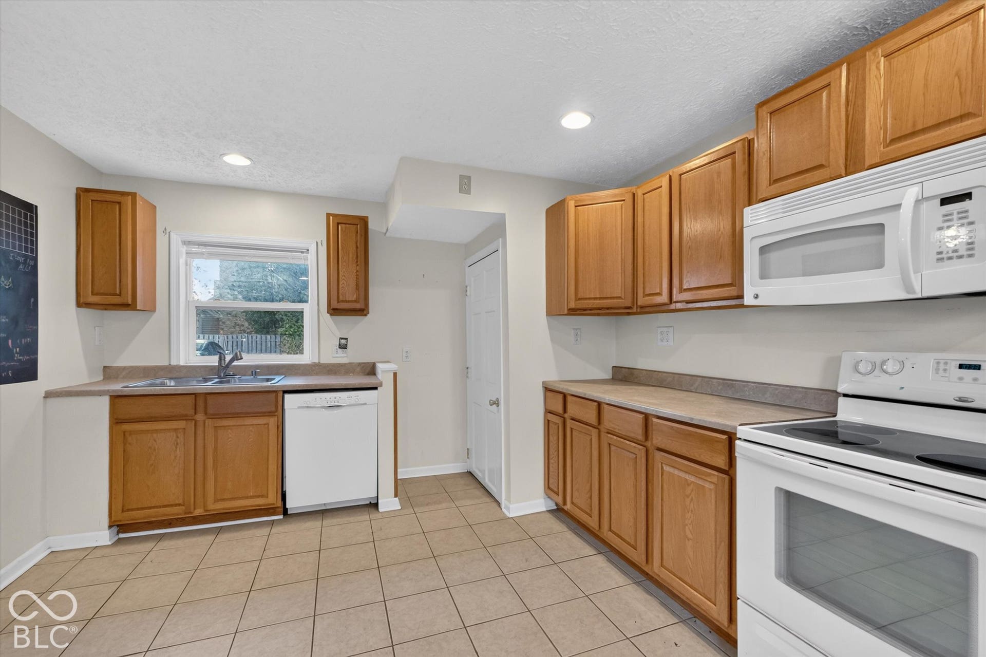 8404 Union Chapel Road, Indianapolis, IN 46240 Kitchen featuring tile flooring, wood-finish cabinetry, white appliances, a double basin sink, and ample countertop space