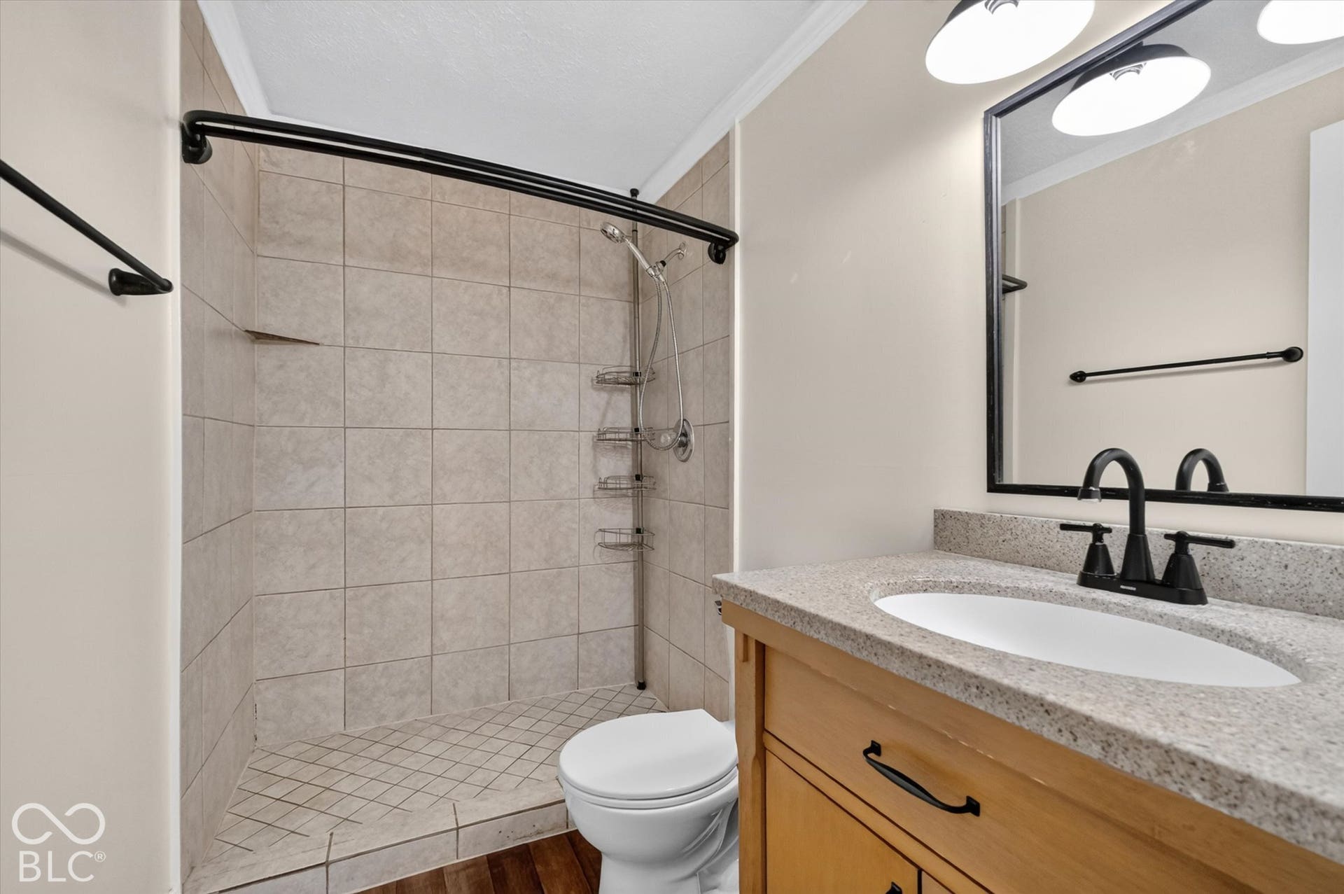 8404 Union Chapel Road, Indianapolis, IN 46240 Walk-in shower with tiled walls, wood-finish vanity with countertop, oval undermount sink, and matte black fixtures