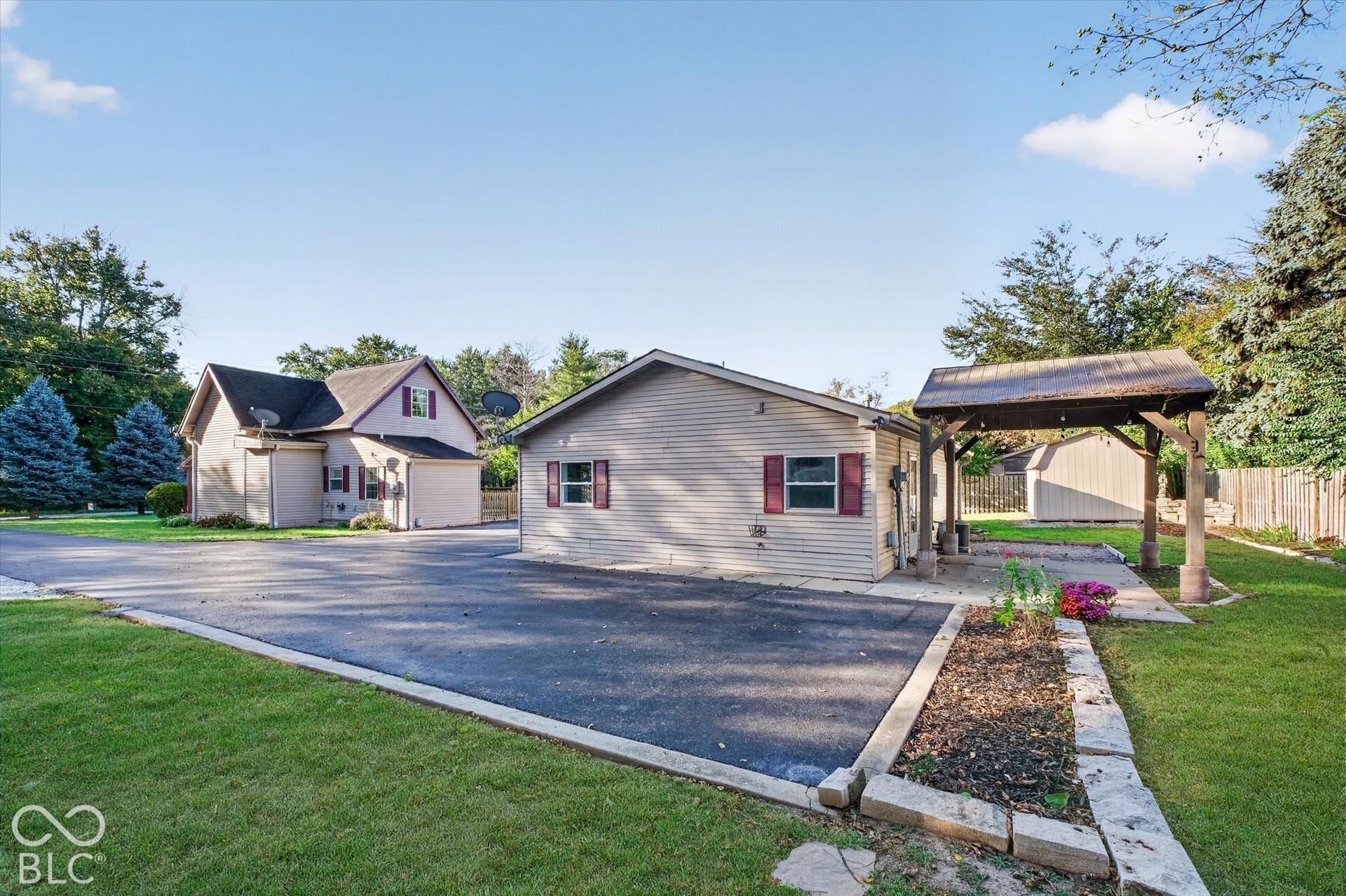 8404 Union Chapel Road, Indianapolis, IN 46240 Expansive asphalt paving, detached accessory building with vinyl siding, covered outdoor structure, landscaped garden bed