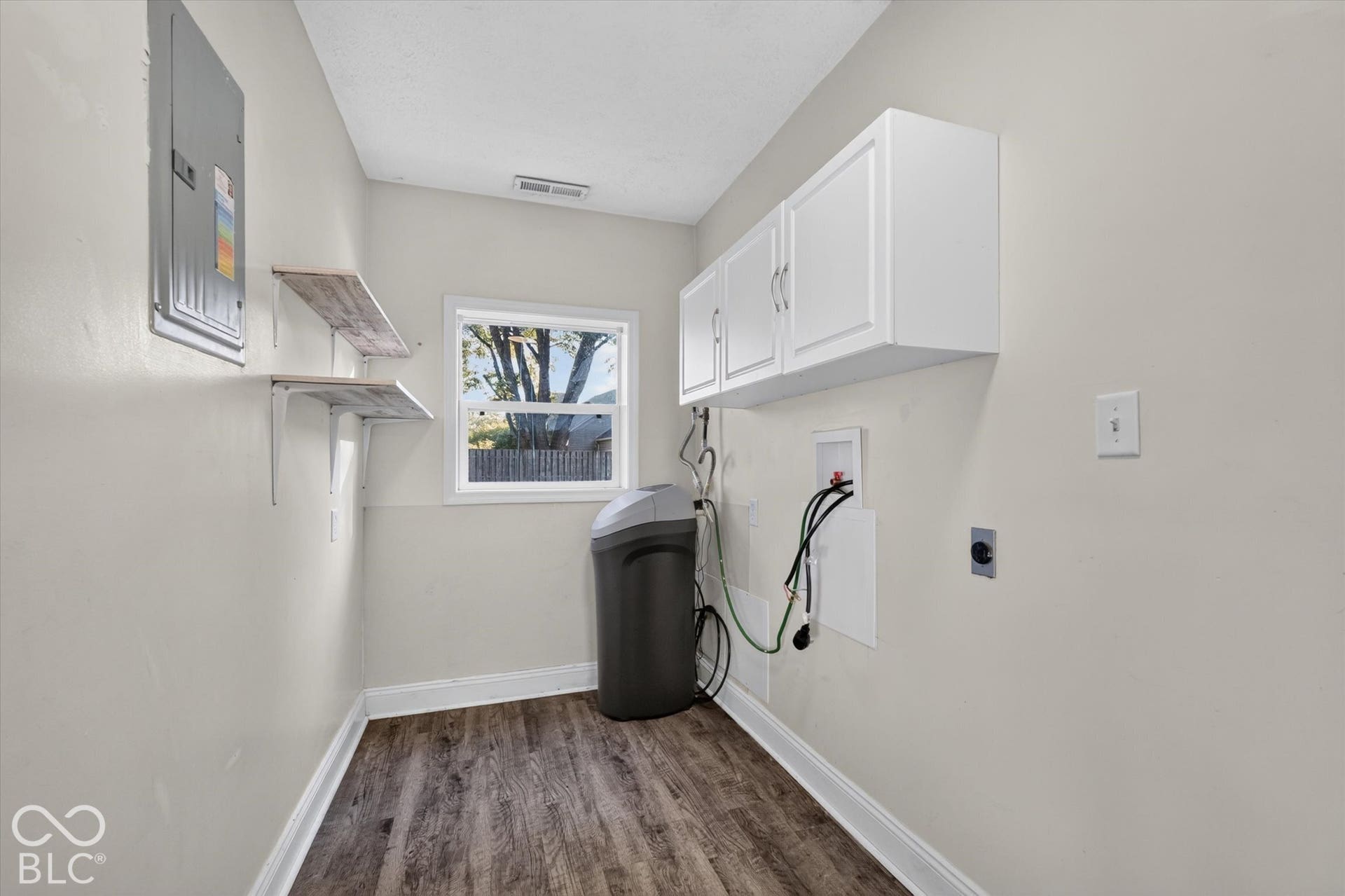 8404 Union Chapel Road, Indianapolis, IN 46240 Laundry area with LVP flooring, white cabinetry, and wall-mounted shelving
