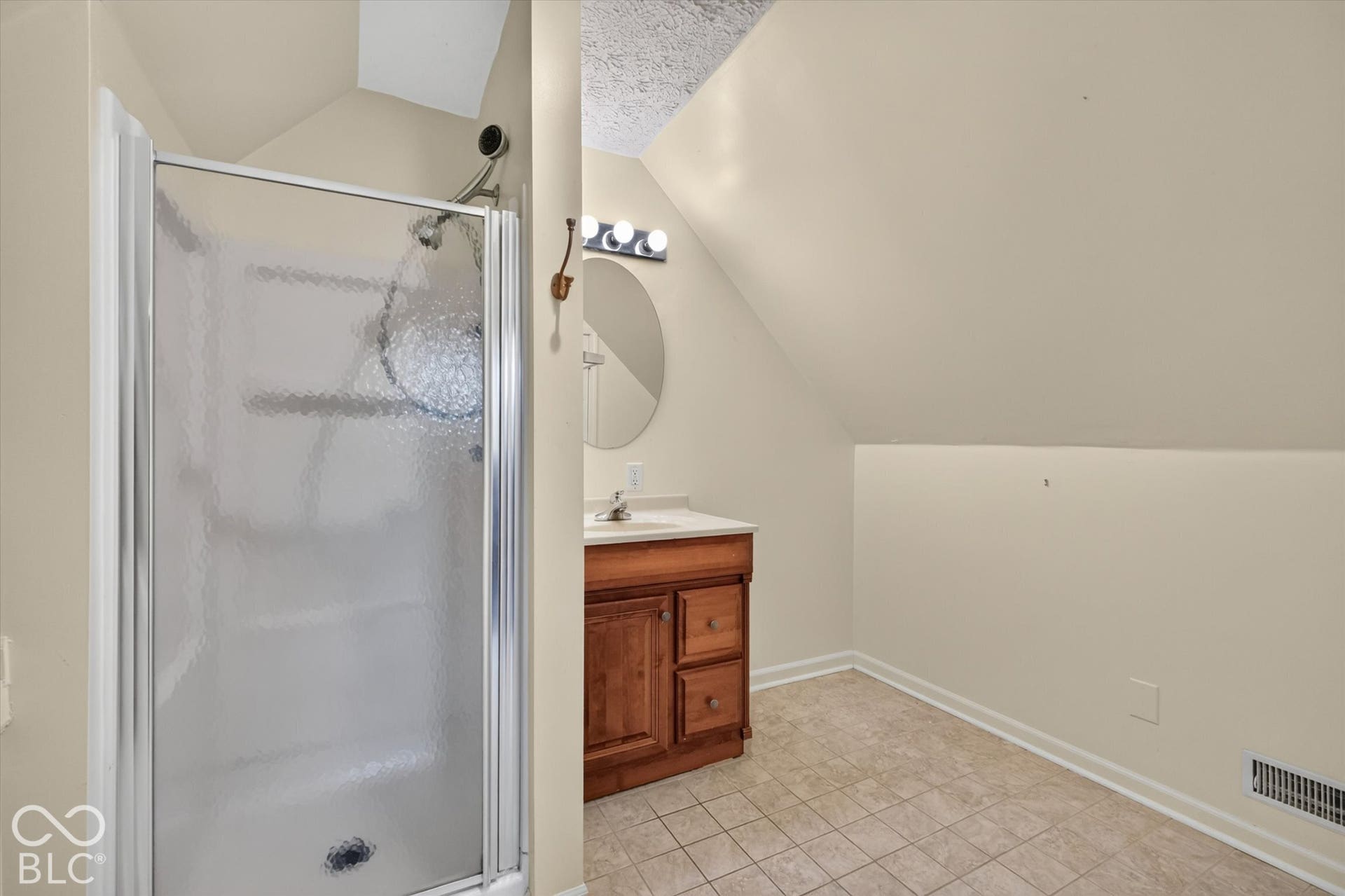 8404 Union Chapel Road, Indianapolis, IN 46240 Shower enclosure with a clear glass door, single vanity with wood-finish cabinetry, and neutral-toned floor tile