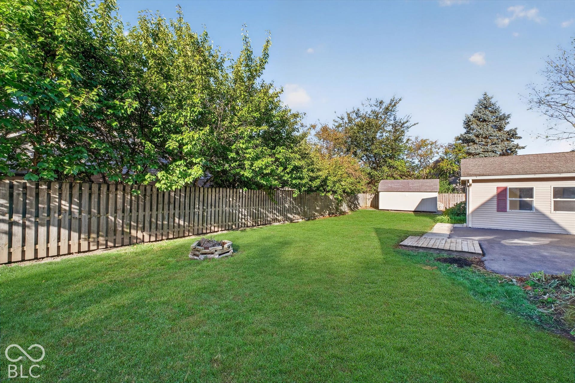 8404 Union Chapel Road, Indianapolis, IN 46240 Expansive lawn with a wood privacy fence, stone fire pit, and an exterior storage sheds