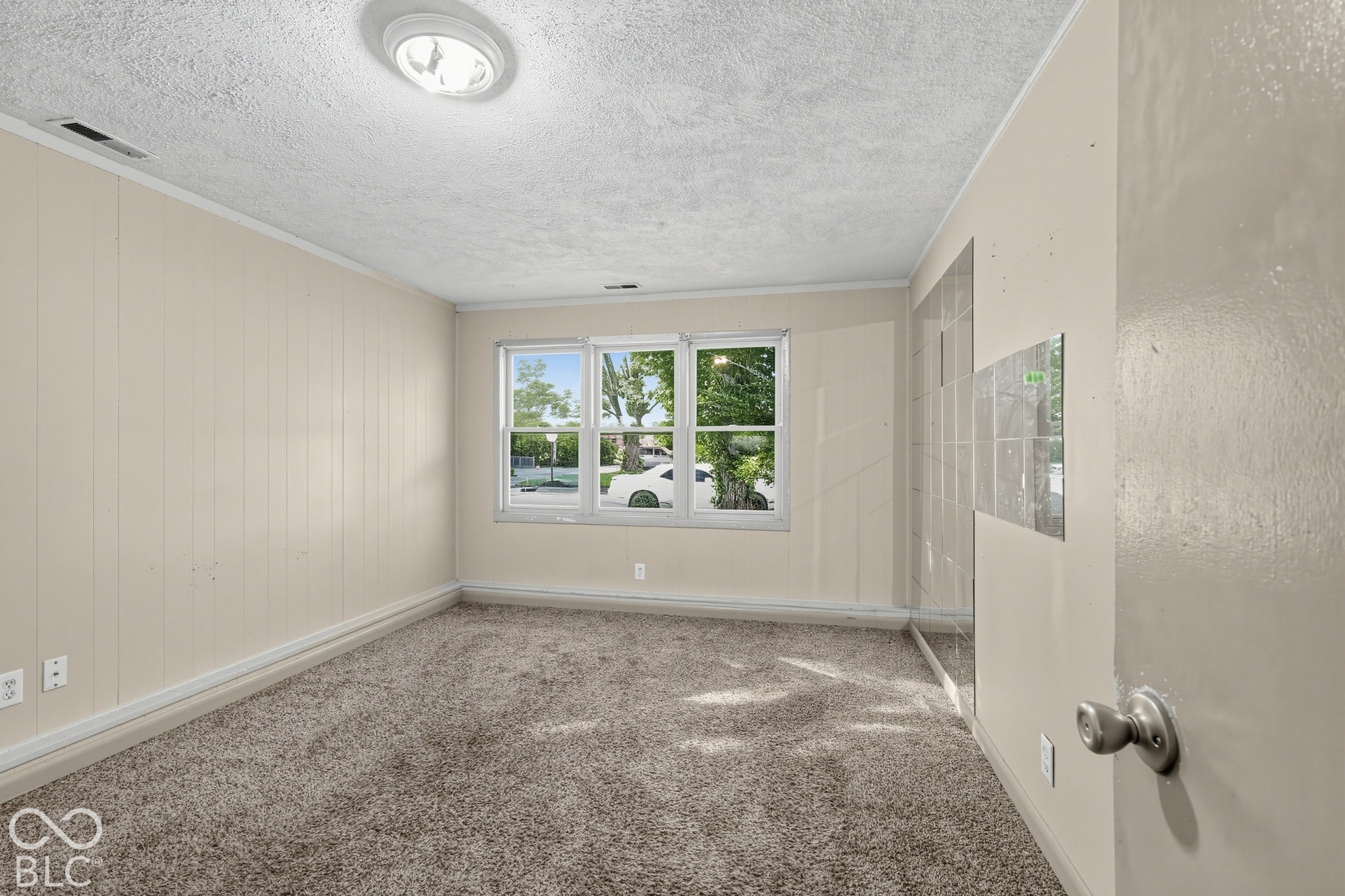 Recessed lighting and a window with natural light complement the textured ceiling