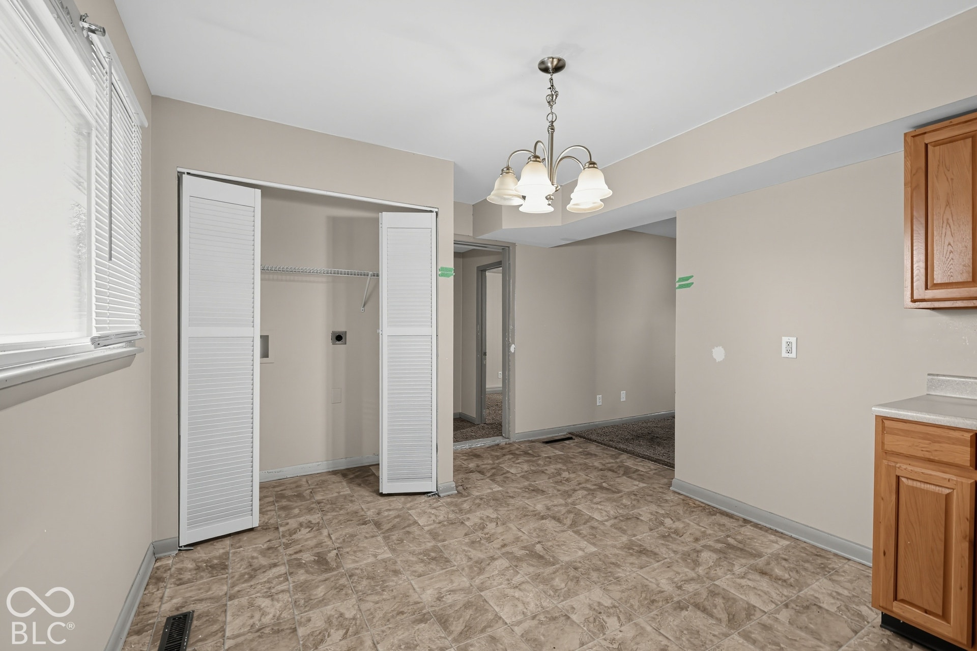 Laundry closet with bi-fold louvered doors, overhead shelving, and utility hookups
