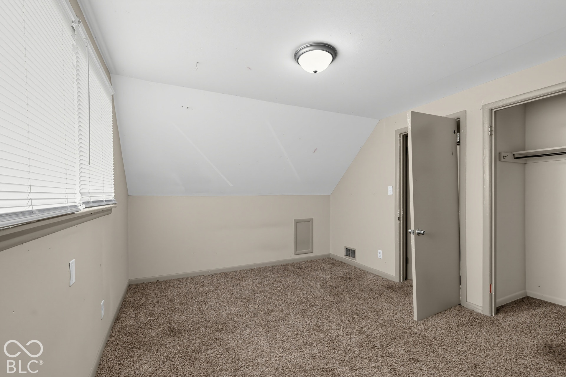Wall-to-wall carpeting, window with blinds, overhead lighting, and built-in closet
