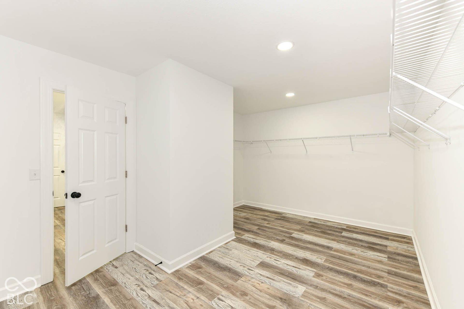 Recessed lighting, wood-finish flooring, white walls, and built-in wire shelving