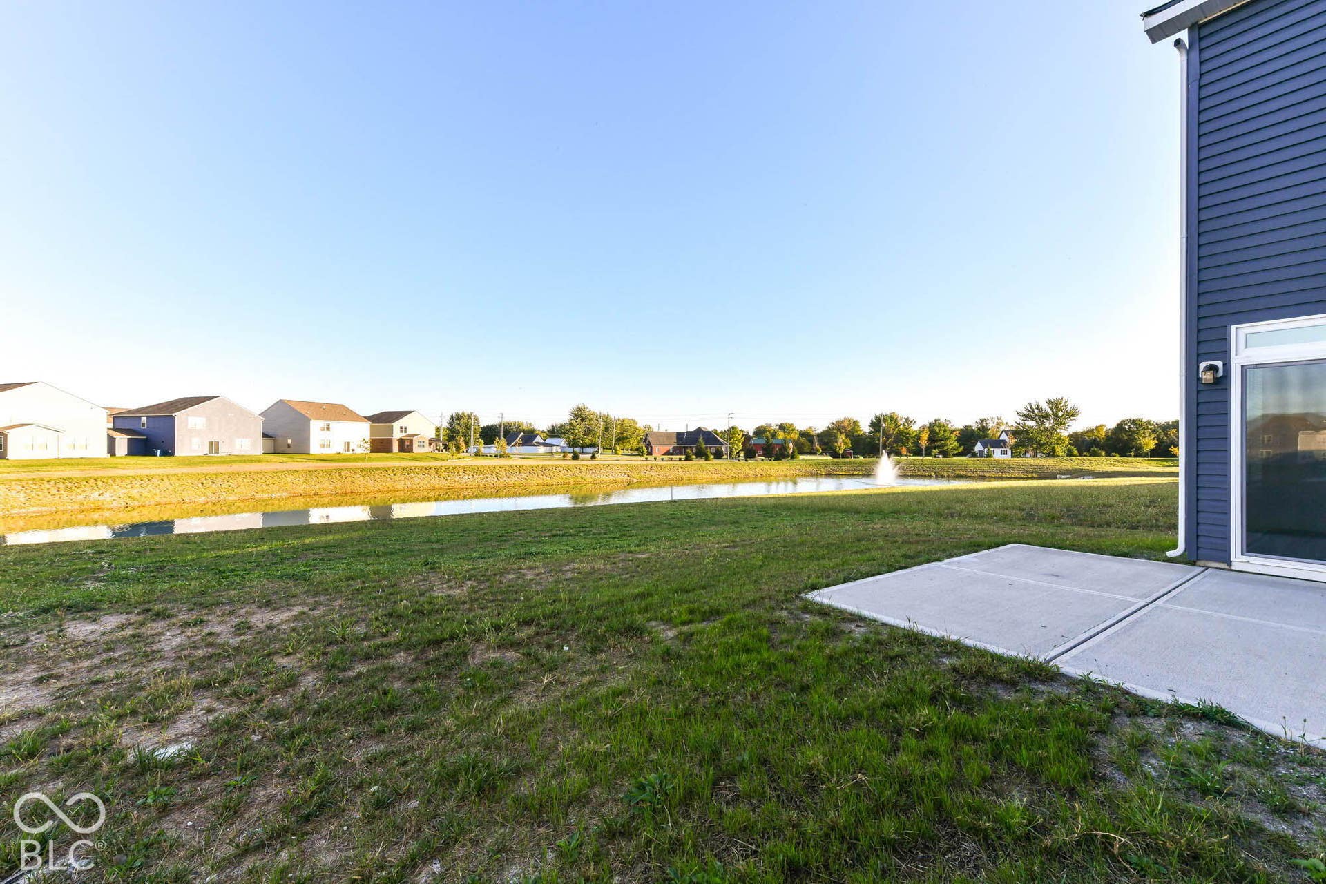 Rear patio with pond, fountain, and adjacent green space