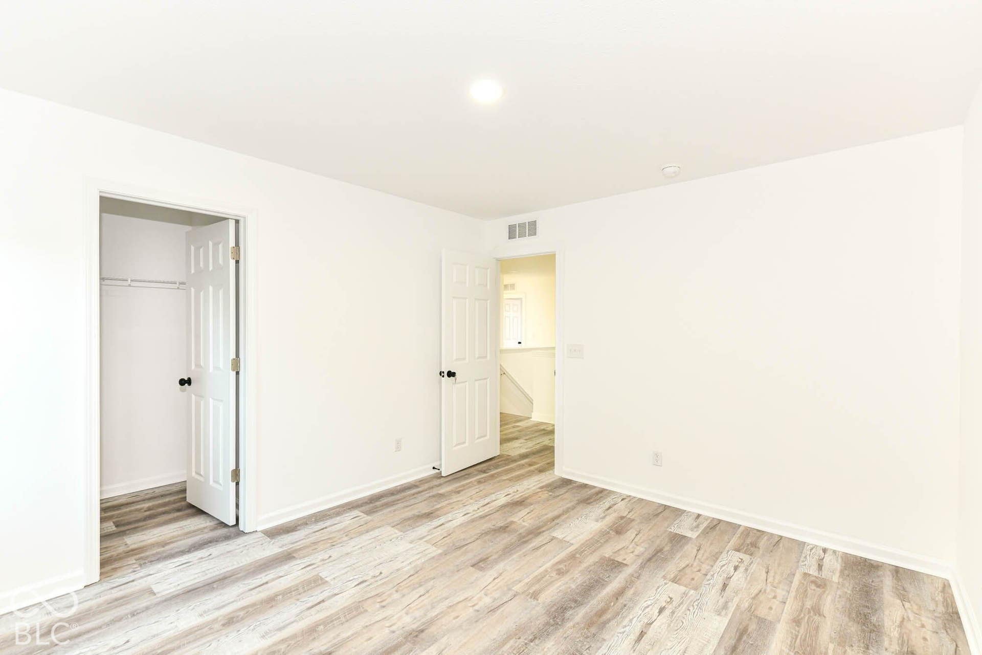 Wood-finish flooring, white walls, and a recessed ceiling light