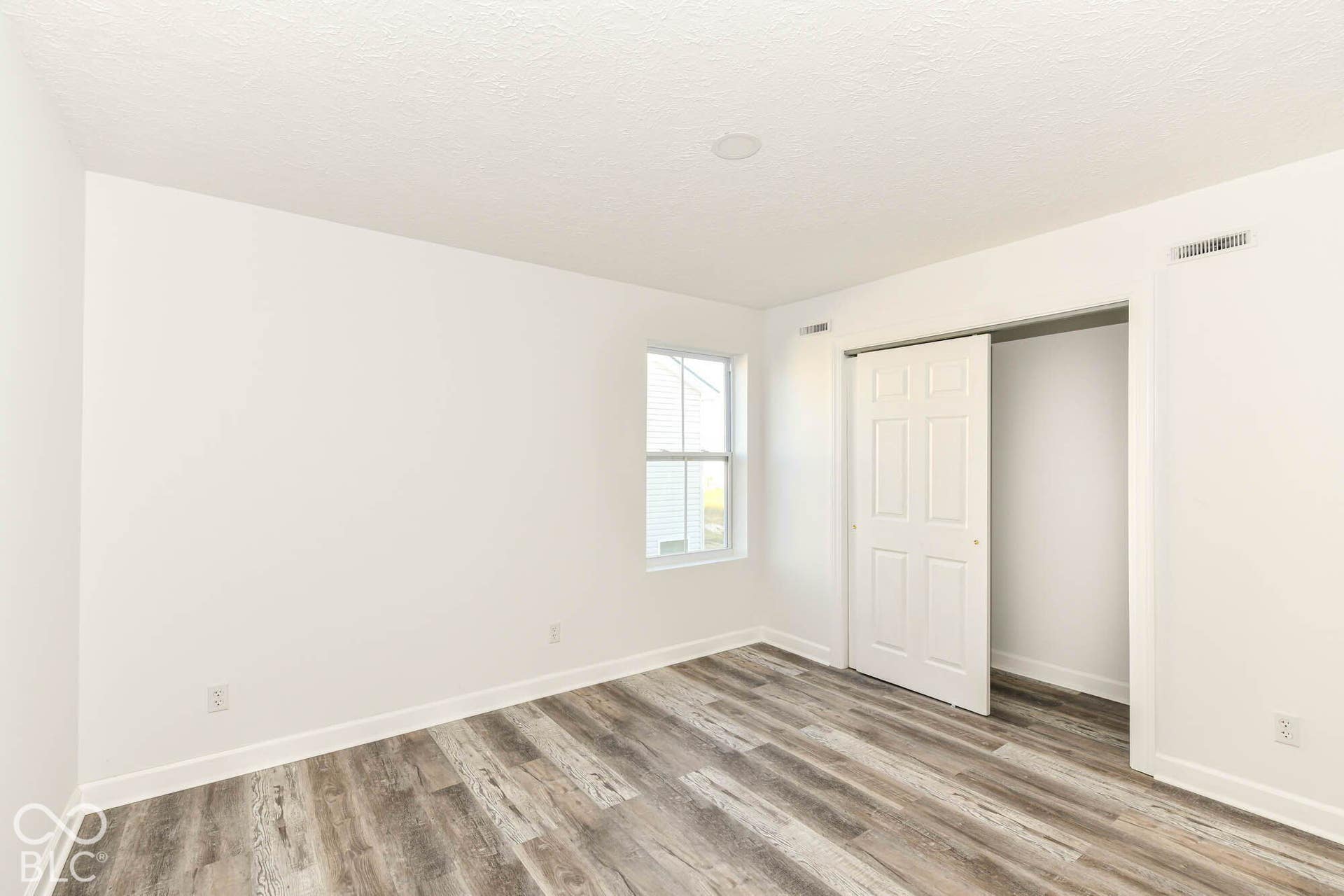 Recessed ceiling lighting, wood-finish flooring, white walls, and a window with white trim