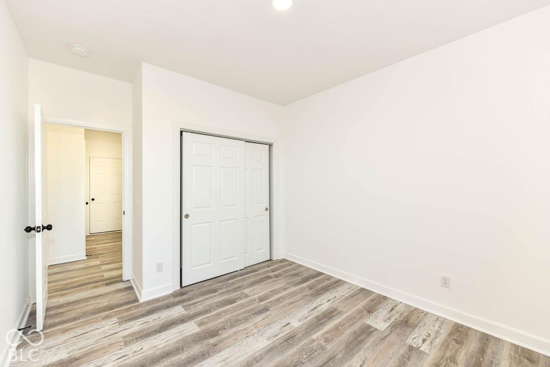 Recessed ceiling lighting illuminates the room with wood-finish flooring and a white sliding closet door