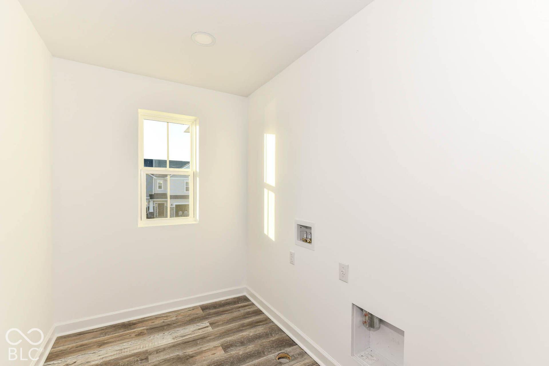 Window with white trim, wood-finish flooring, recessed ceiling lighting, and crisp white walls